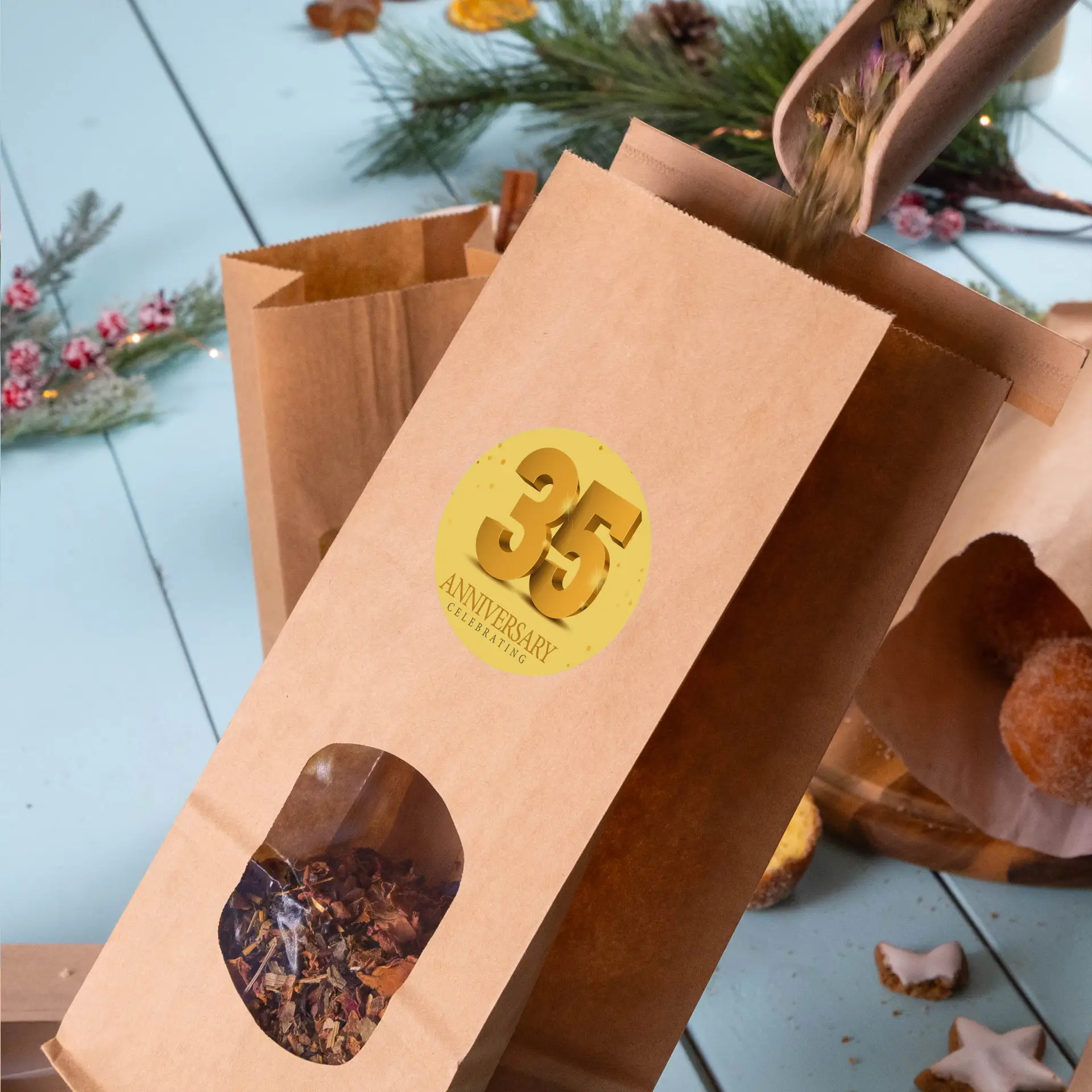 Sac en papier kraft marron avec une fenêtre transparente montrant des herbes séchées et une étiquette ronde dorée indiquant "35 ANS D'ANNIVERSAIRE".