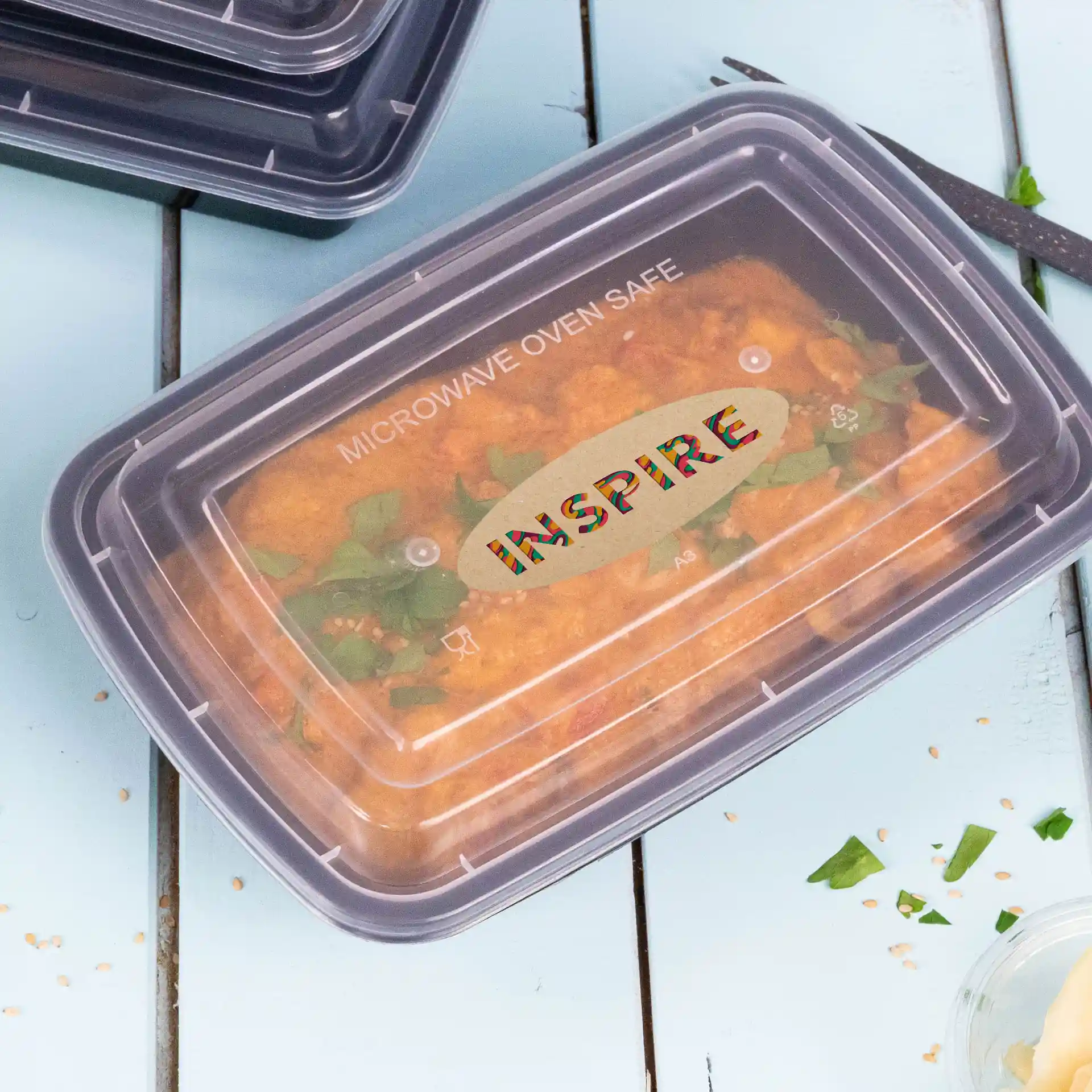 Conteneur avec un couvercle transparent montrant de la nourriture à l'intérieur, étiqueté "SÉCURISÉ POUR MICRO-ONDE" et "INSPIRE" en haut.