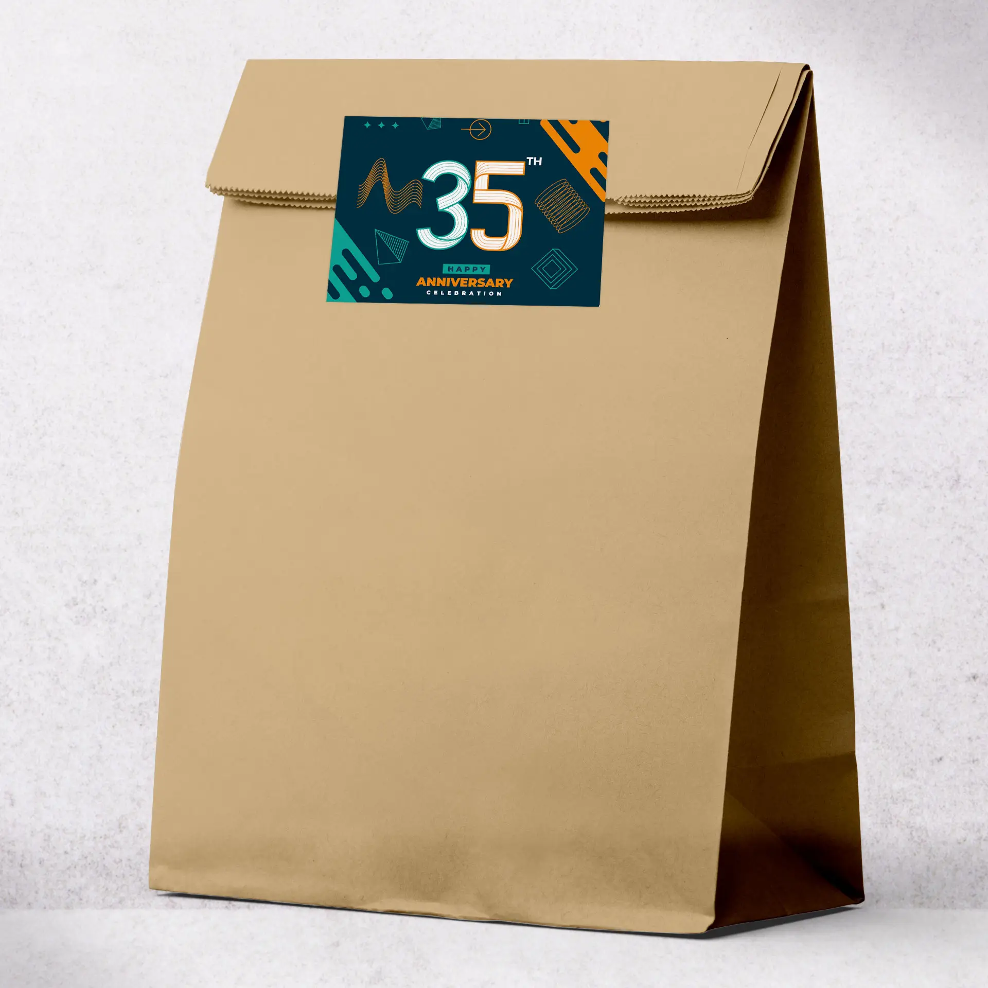 Sac en papier kraft brun avec une étiquette personnalisée présentant un design pour le 35ème anniversaire, adapté aux événements et aux services de livraison.