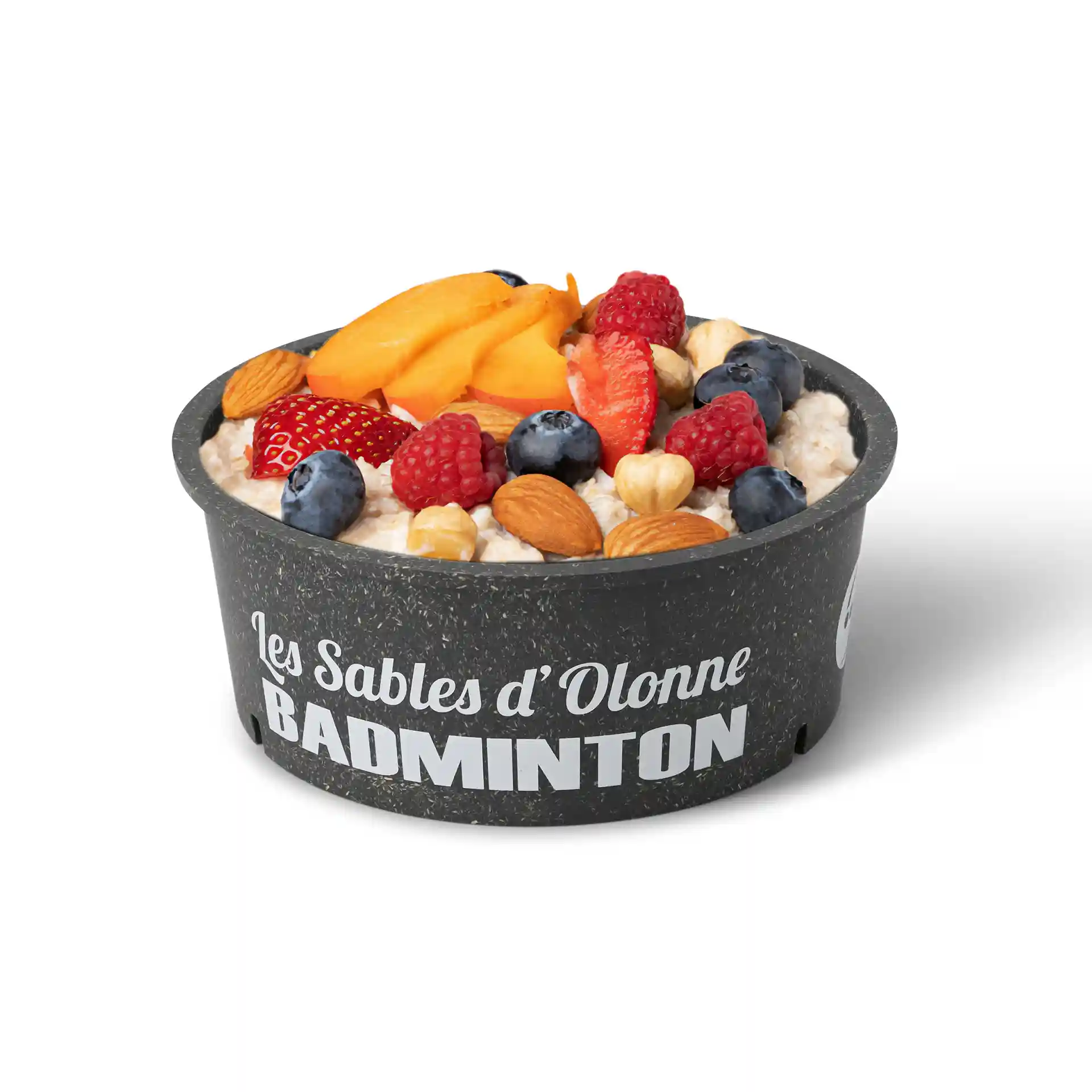 Bol rond gris réutilisable rempli de flocons d'avoine, garni de fruits et de noix, sur fond blanc.