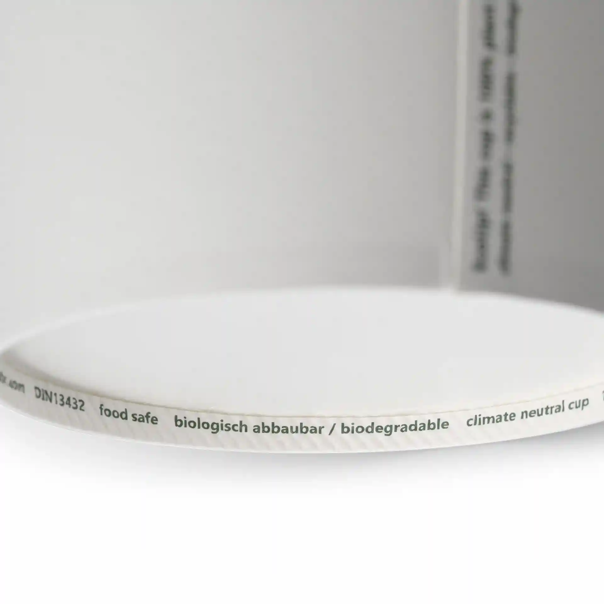 Gros plan du bord d'un contenant à soupe en carton blanc montrant une étiquette avec des marquages et une surface intérieure lisse.