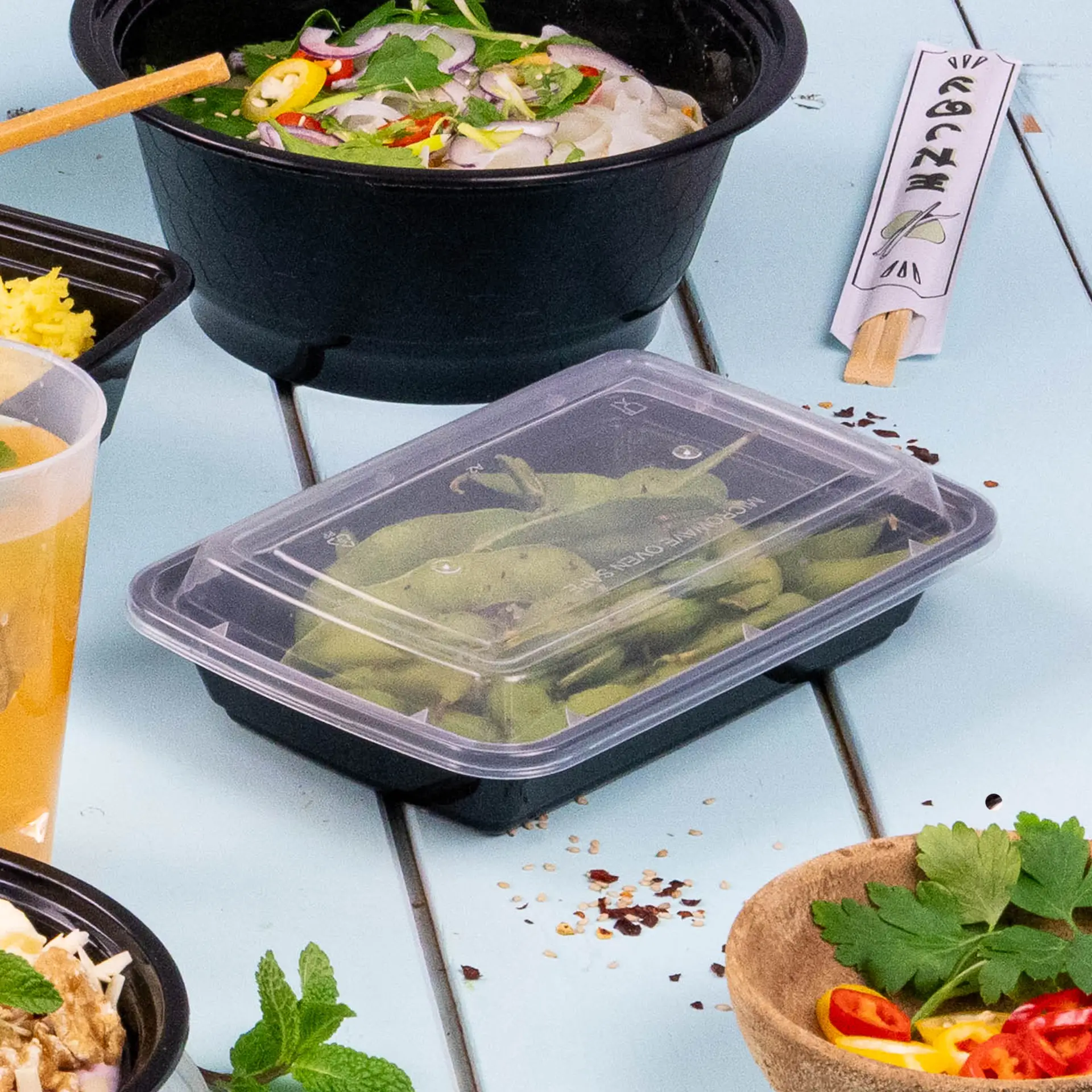 Conteneur rectangulaire noir réutilisable pour plats chauds et froids, compatible micro-ondes et lave-vaisselle, avec couvercle transparent.