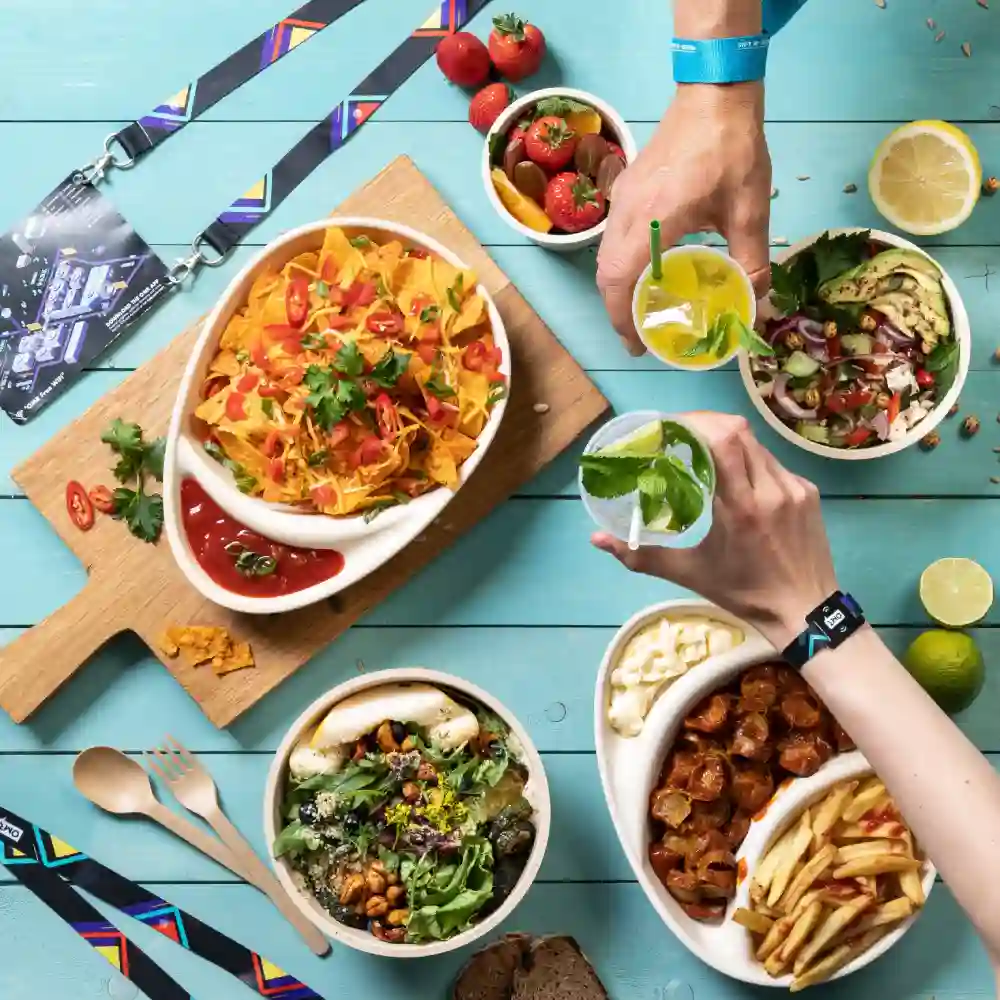 Vue de dessus de divers aliments, y compris des nachos, des salades et des boissons sur une surface bleue avec des cordons et des ustensiles.