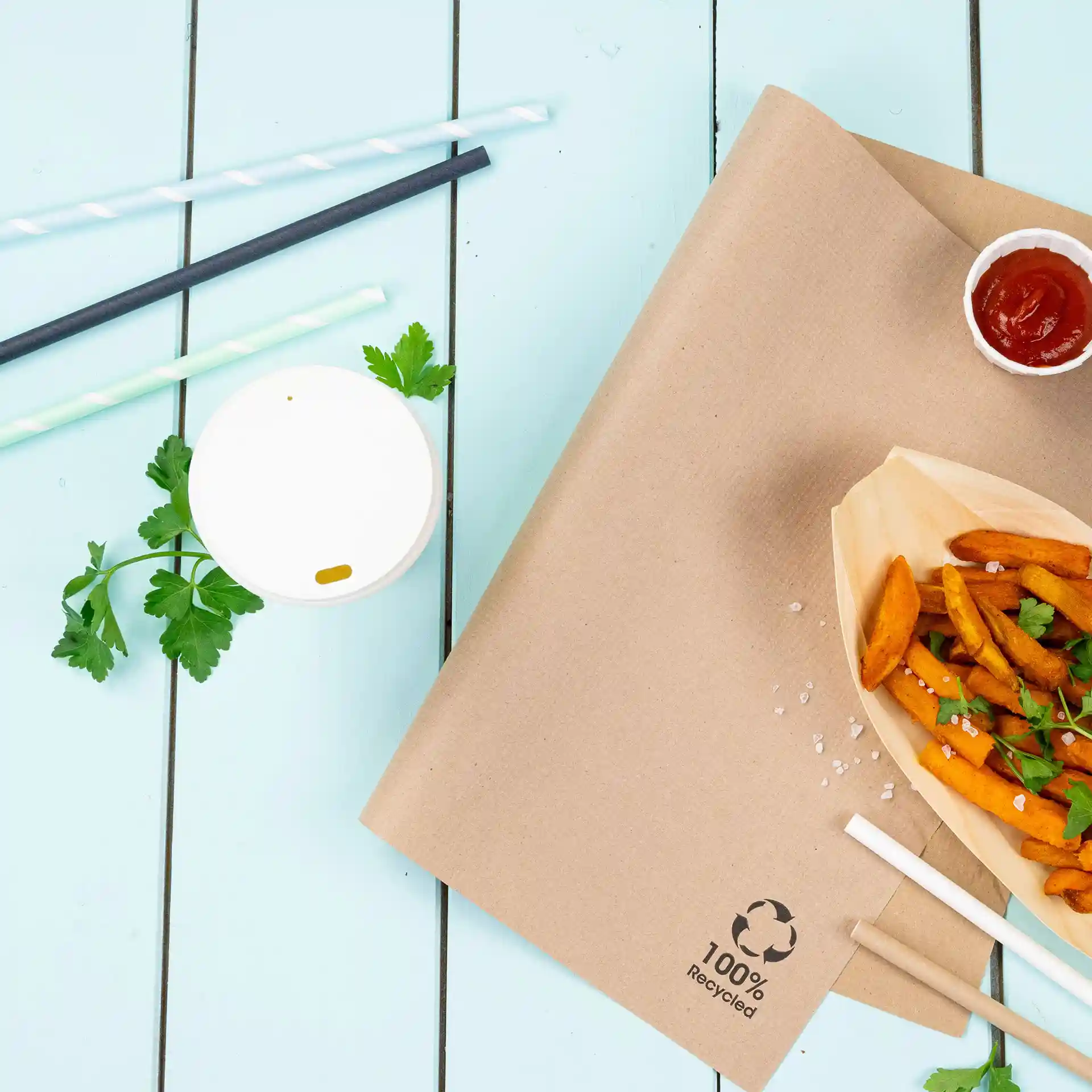 Image d'une feuille de papier brun avec un contenant de frites, un petit gobelet de ketchup, un gobelet blanc et plusieurs pailles en papier.