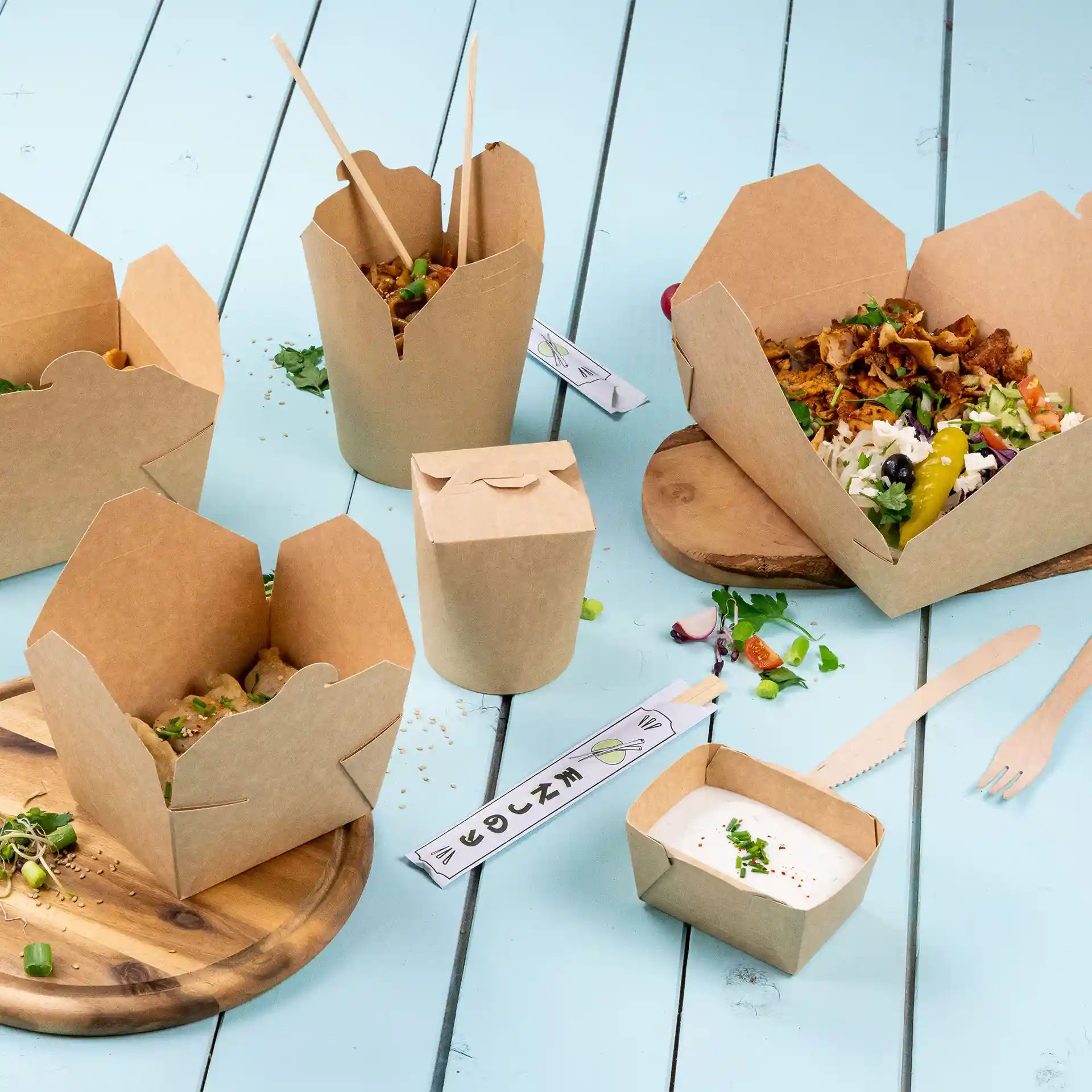 Image de plusieurs contenants alimentaires en carton brun, y compris une boîte rectangulaire avec un couvercle, sur une surface bleue.