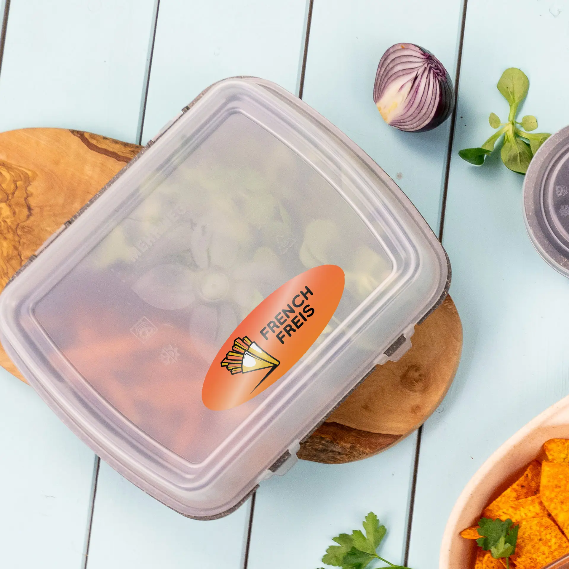 Étiquette ovale claire avec le texte "FRENCH FRIES" sur un contenant, entourée d'ingrédients frais sur une planche en bois.