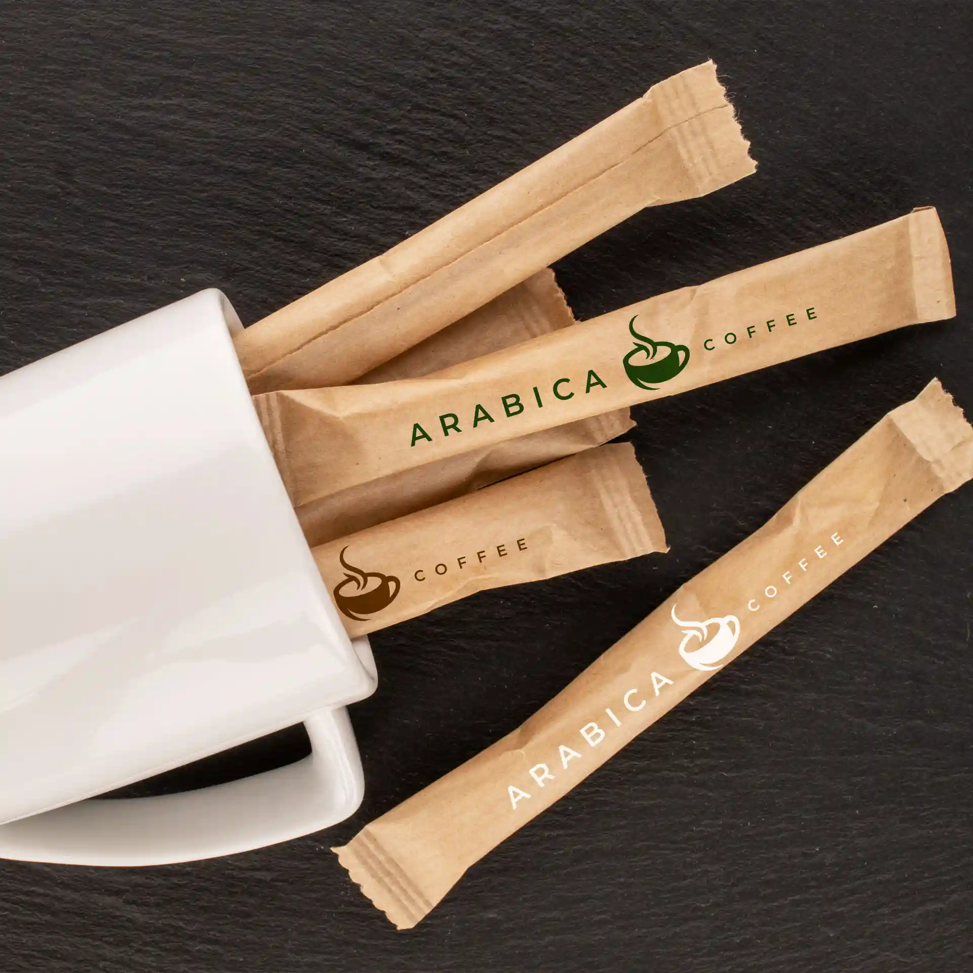 Une tasse blanche avec plusieurs bâtonnets de sucre portant le logo, placée sur une surface sombre.