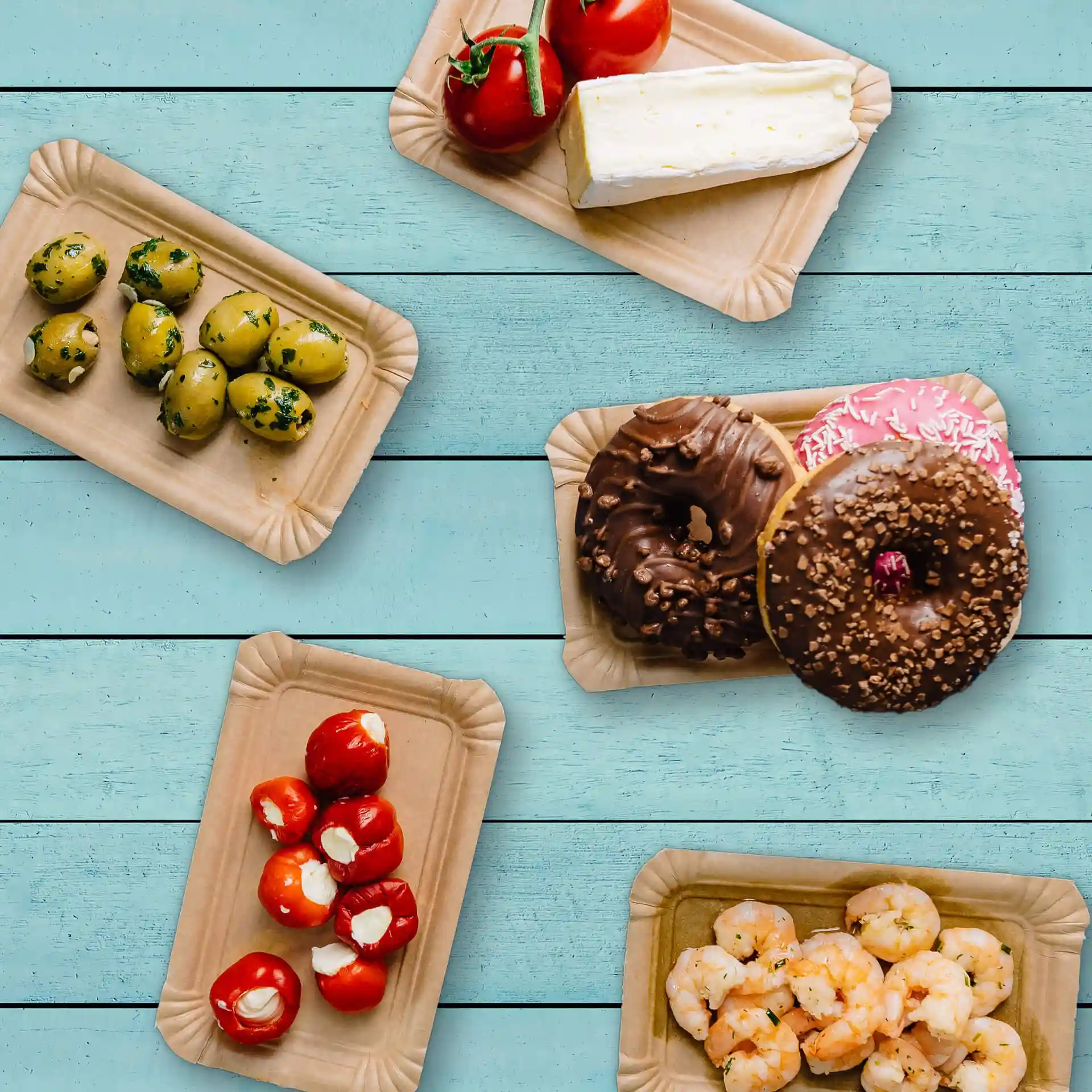 Image de plusieurs assiettes rectangulaires en carton brun avec divers aliments : olives, tomates, fromage, beignets et crevettes.