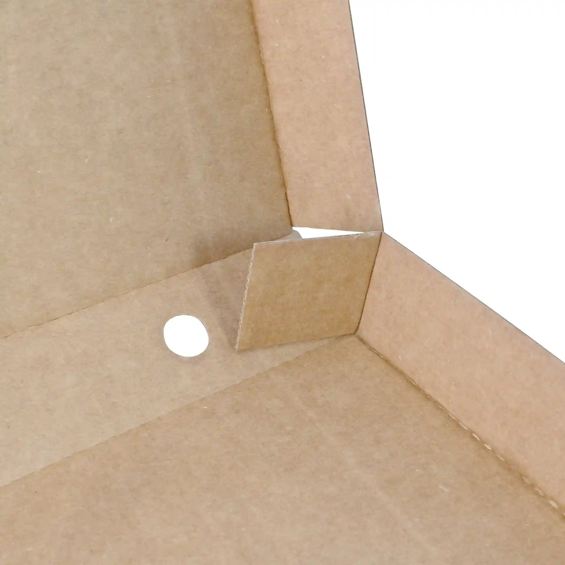 Gros plan d'un coin de boîte à pizza en carton brun avec un onglet découpé et un trou circulaire.