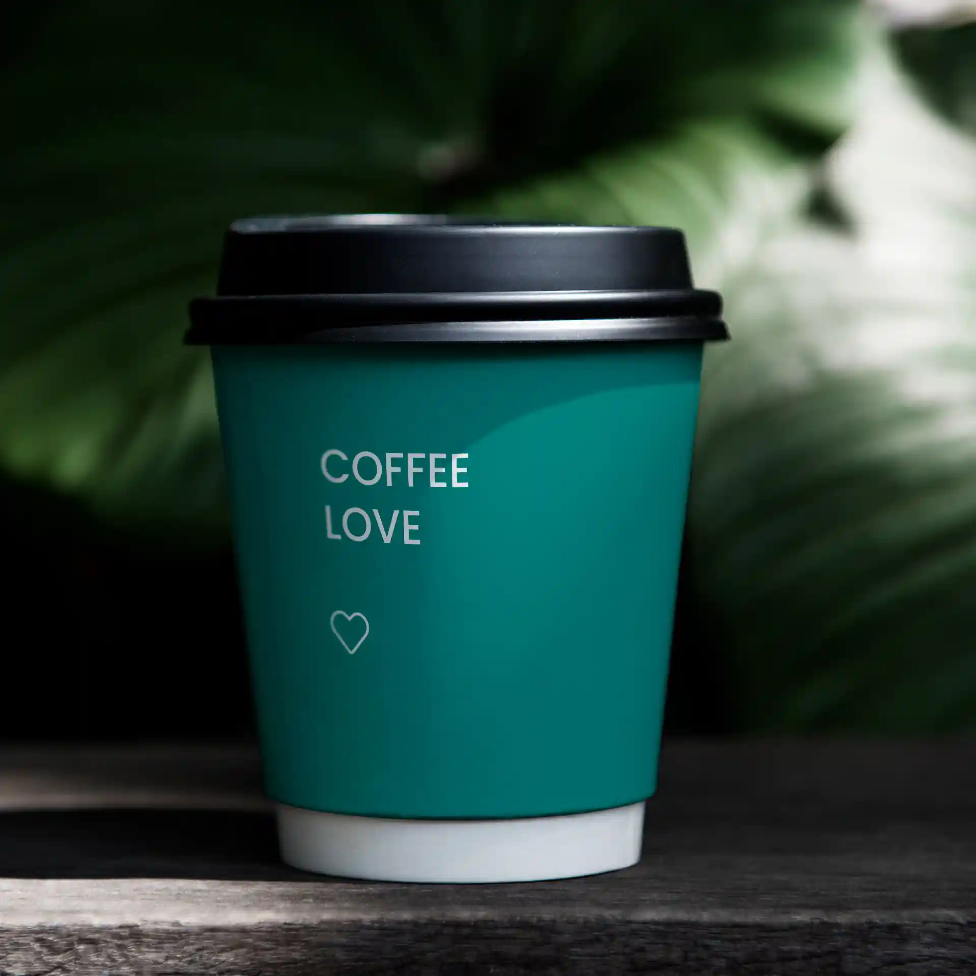 Gobelet en papier teal avec un couvercle noir, portant le texte "COFFEE LOVE" et un symbole de cœur.