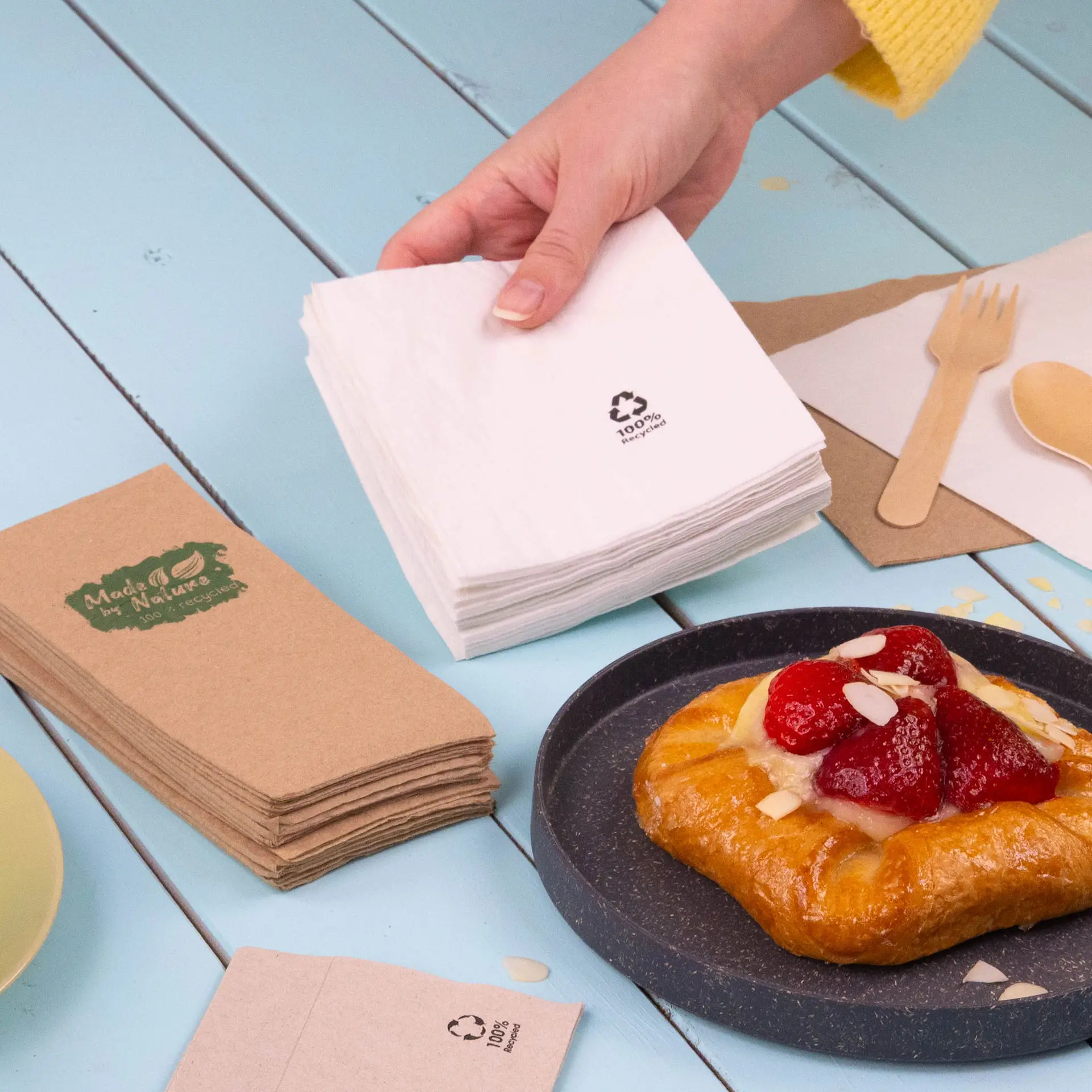 Deux serviettes de cocktail carrées, l'une blanche et l'autre grise claire, en papier recyclé, avec des symboles de recyclage.