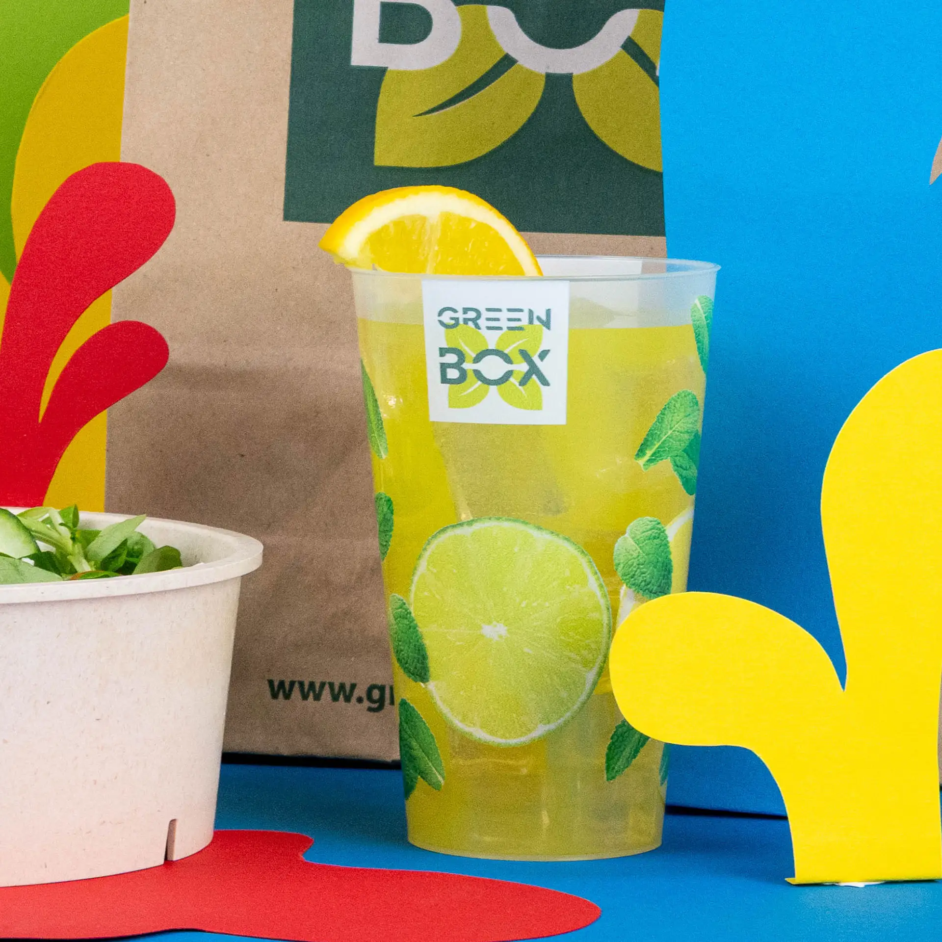 Gobelet réutilisable avec logo, 400 ml, rempli de bière, à côté d'un burger et d'une salade, sur une table en bois.
