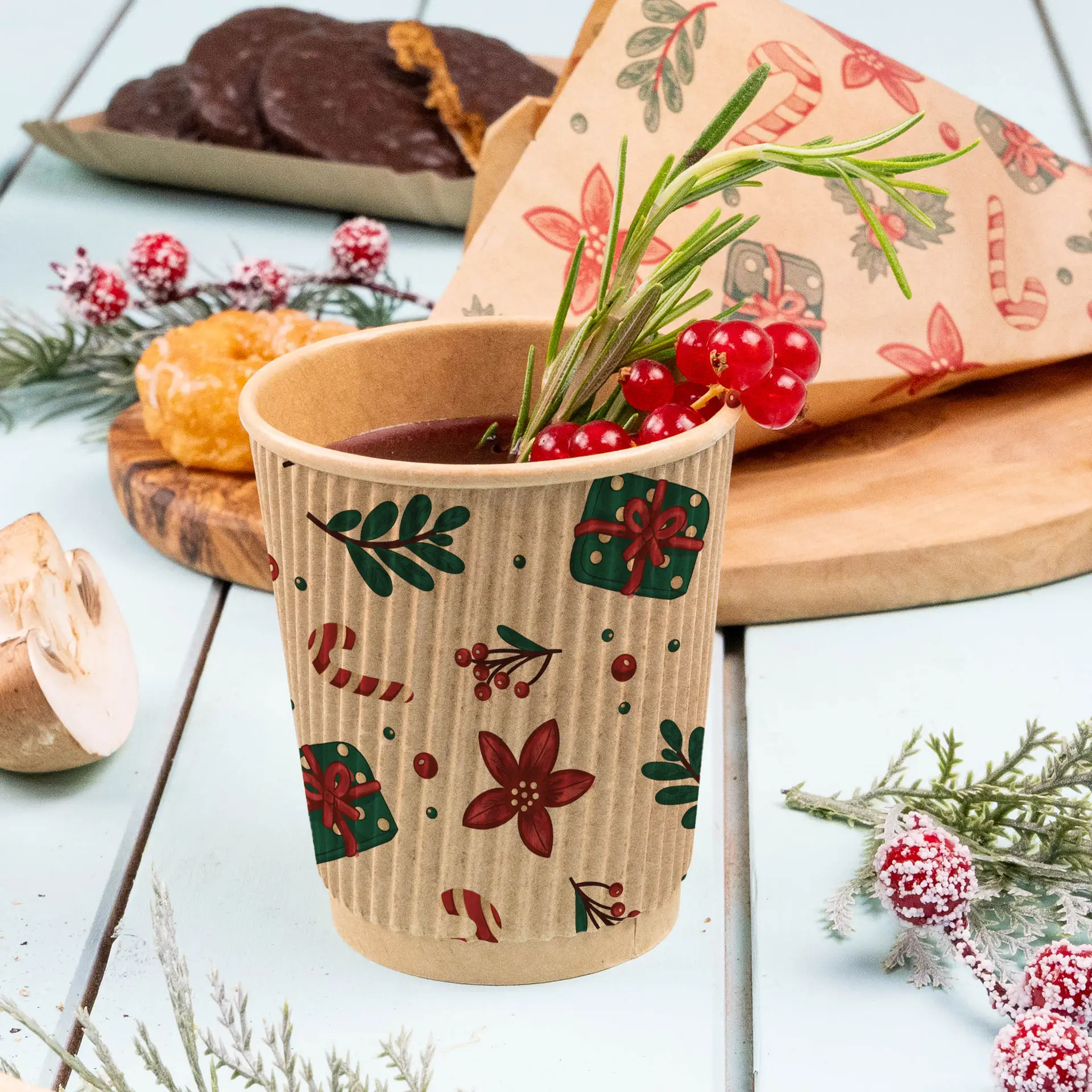 Gobelet ondulé marron avec un design d'hiver, rempli d'une boisson et garni de baies et d'herbes, sur une surface bleu clair.