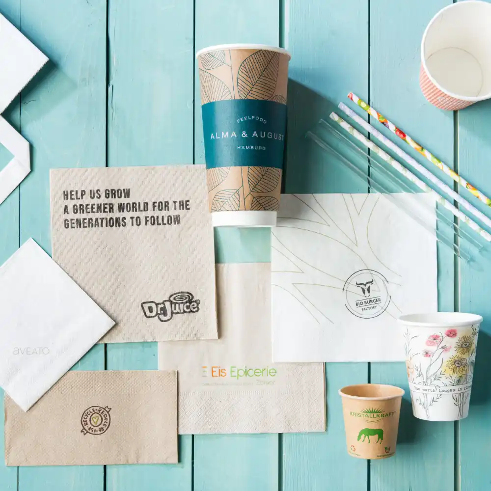 Une variété de matériaux d'emballage imprimés, y compris des cups, des serviettes et des pailles sur une surface en bois.