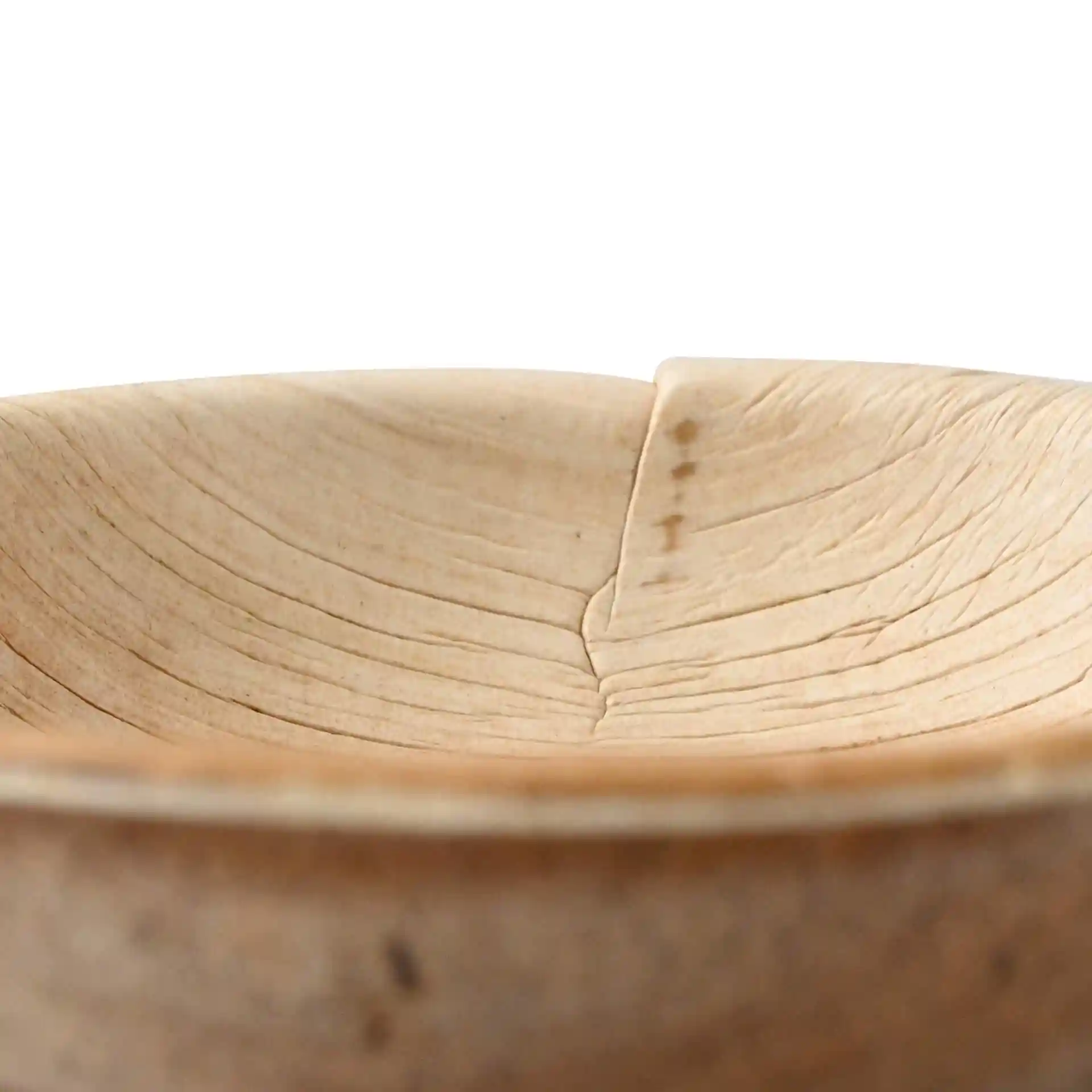 Gros plan d'un bol rond en feuille de palmier avec une texture granuleuse, montrant l'intérieur et une légère couture.