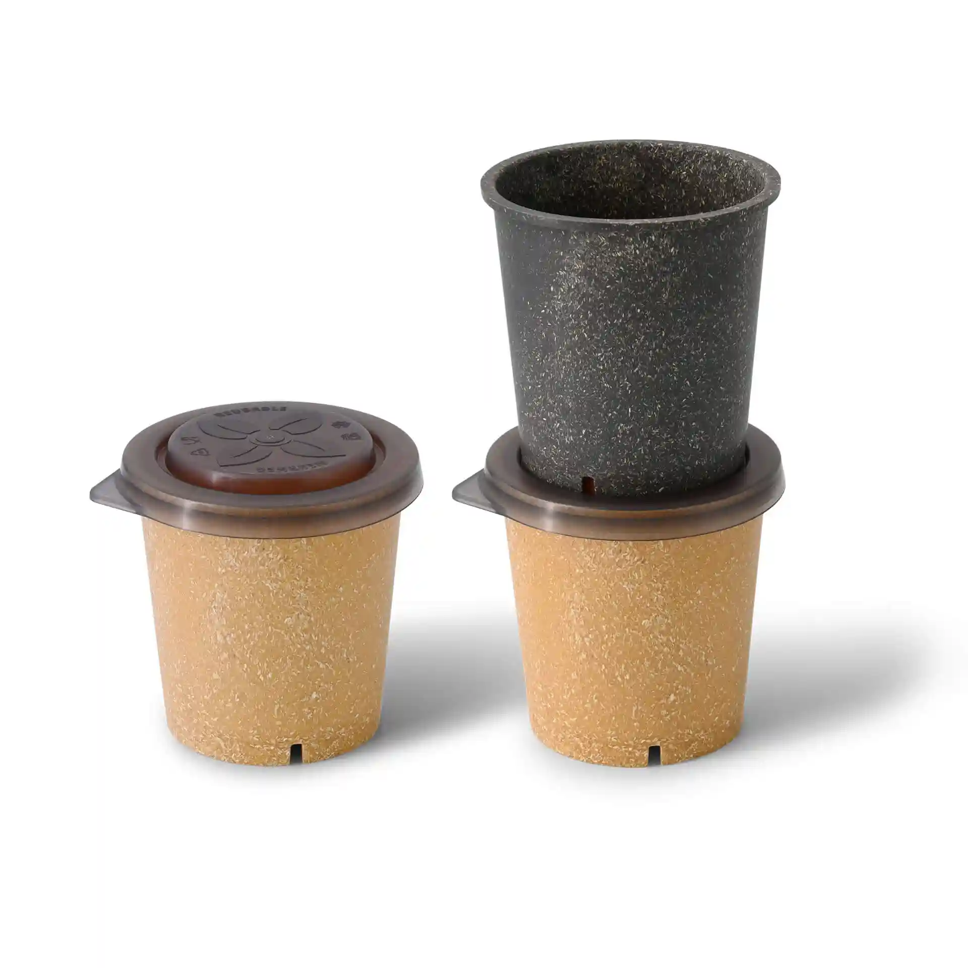 Trois gobelets réutilisables beige et noir, avec un couvercle marron sur le gobelet du haut, disposés sur un fond uni.