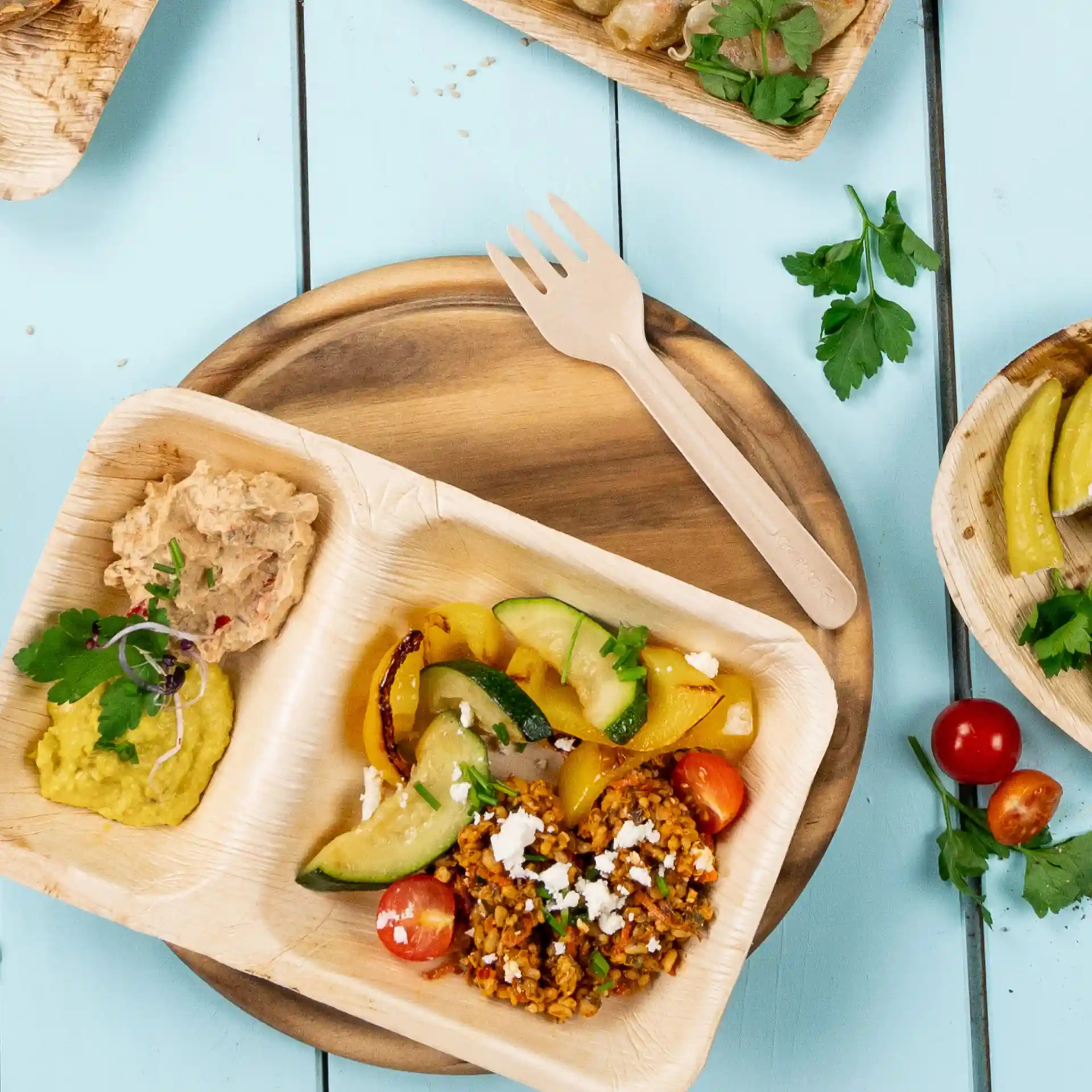 Assiette en papier kraft jetable avec légumes, céréales et dips assortis, accompagnée d'une fourchette en papier brun.