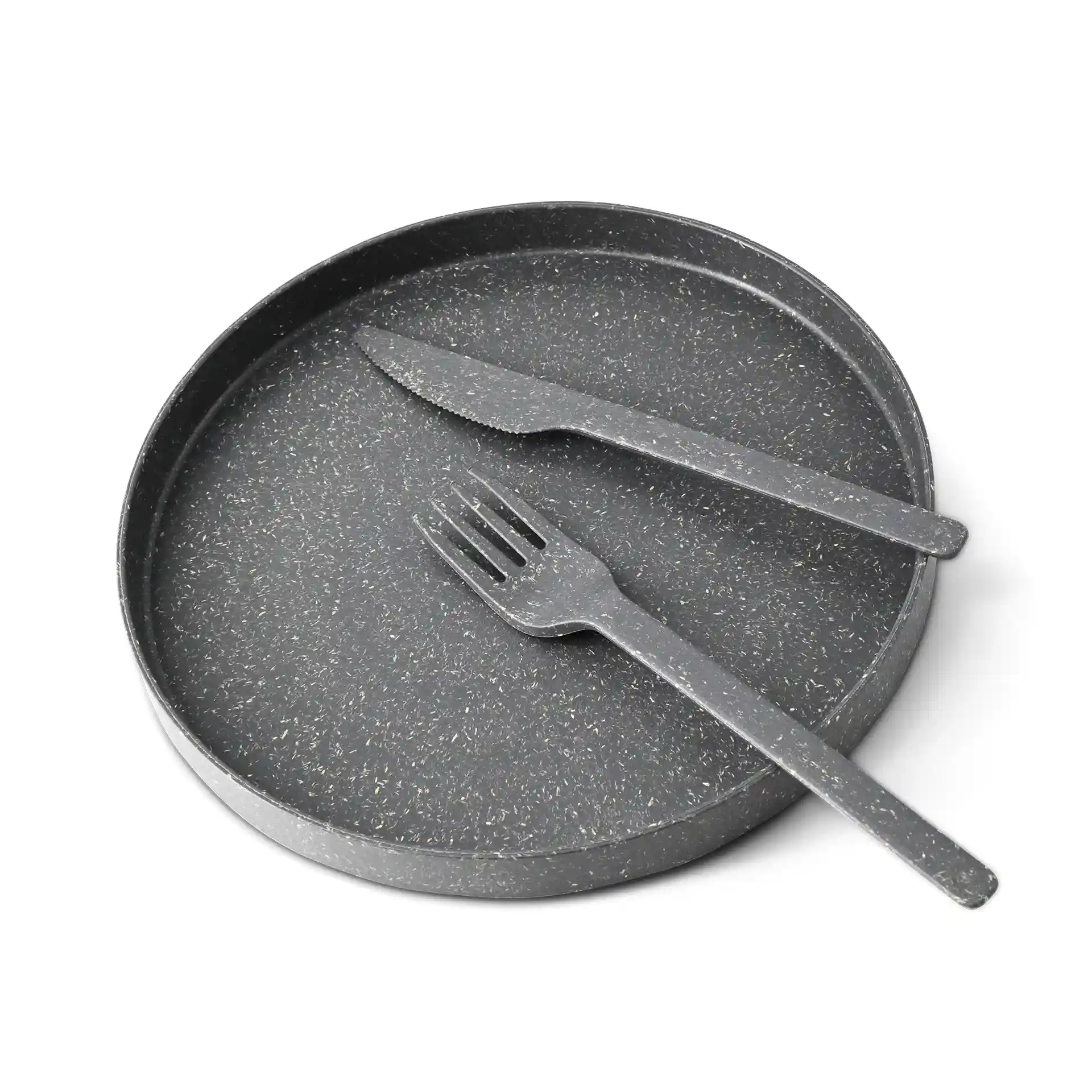 Plateau rond noir avec une surface texturée, accompagné d'un couteau et d'une fourchette en matériau bio.