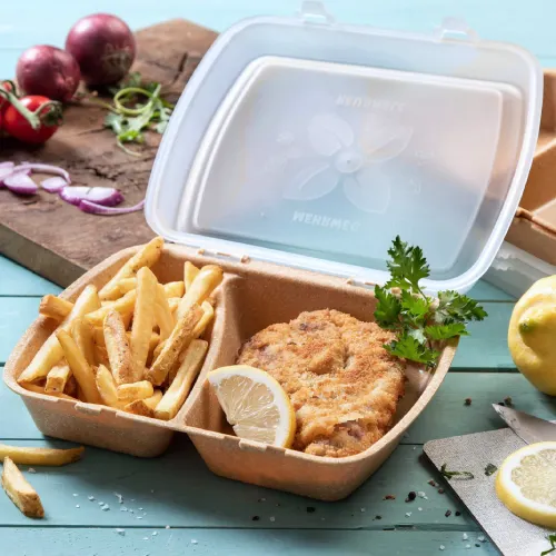 Contenant avec du poulet frit, un quartier de citron et des frites, entouré d'articles alimentaires et d'une planche à découper.