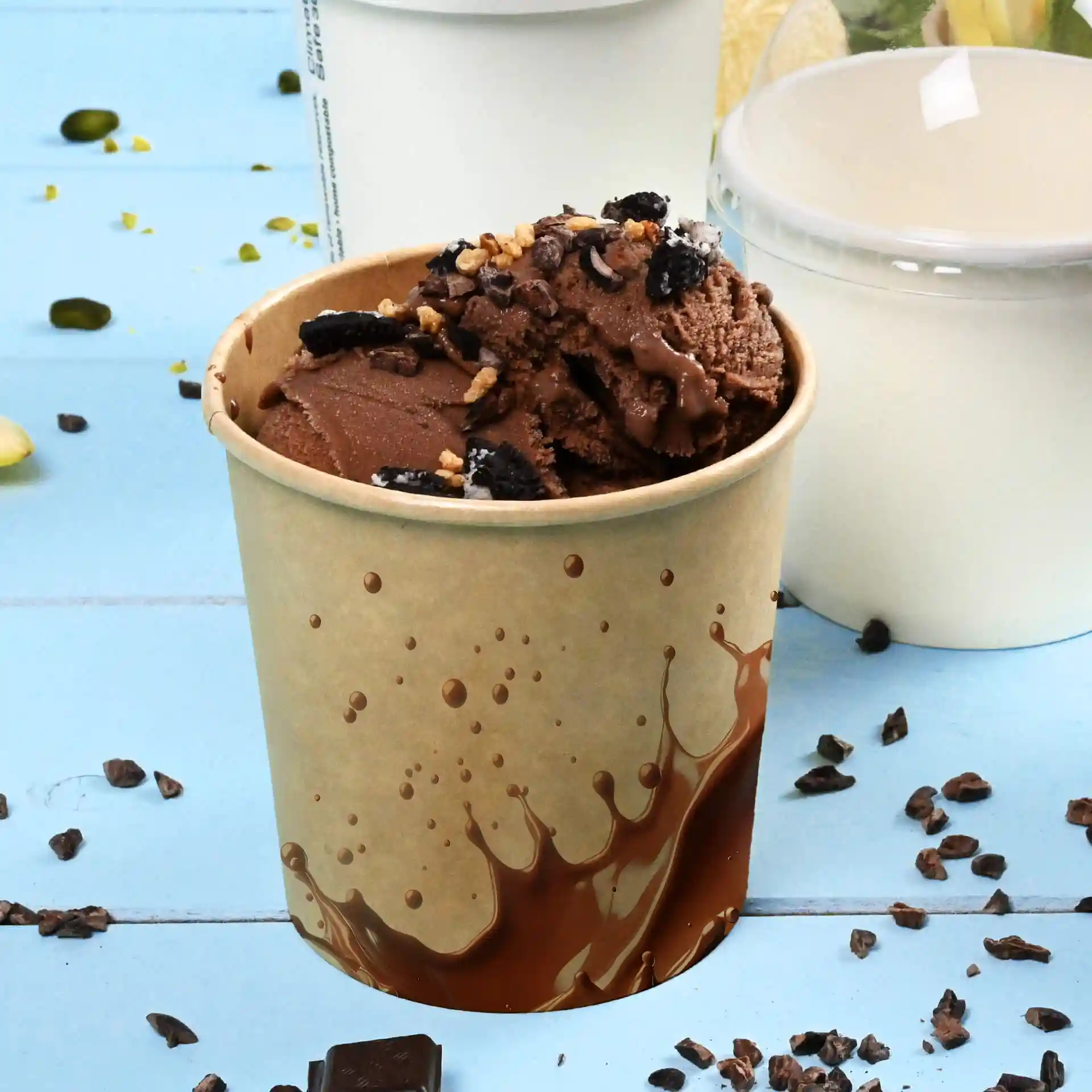 Gobelet en carton marron rempli de glace au chocolat, garni de morceaux de chocolat, sur fond bleu.