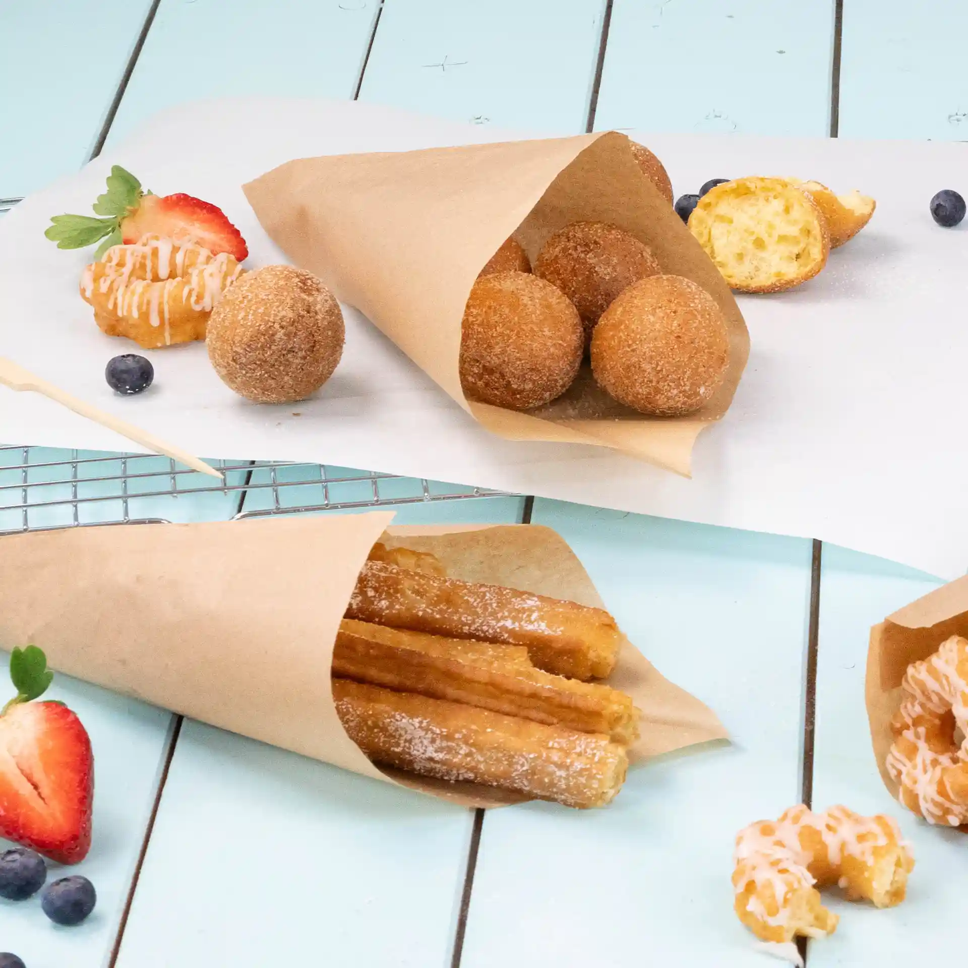 Image de sacs en papier brun contenant des collations frites, y compris des churros et des boules de beignets, sur une surface bleu clair.