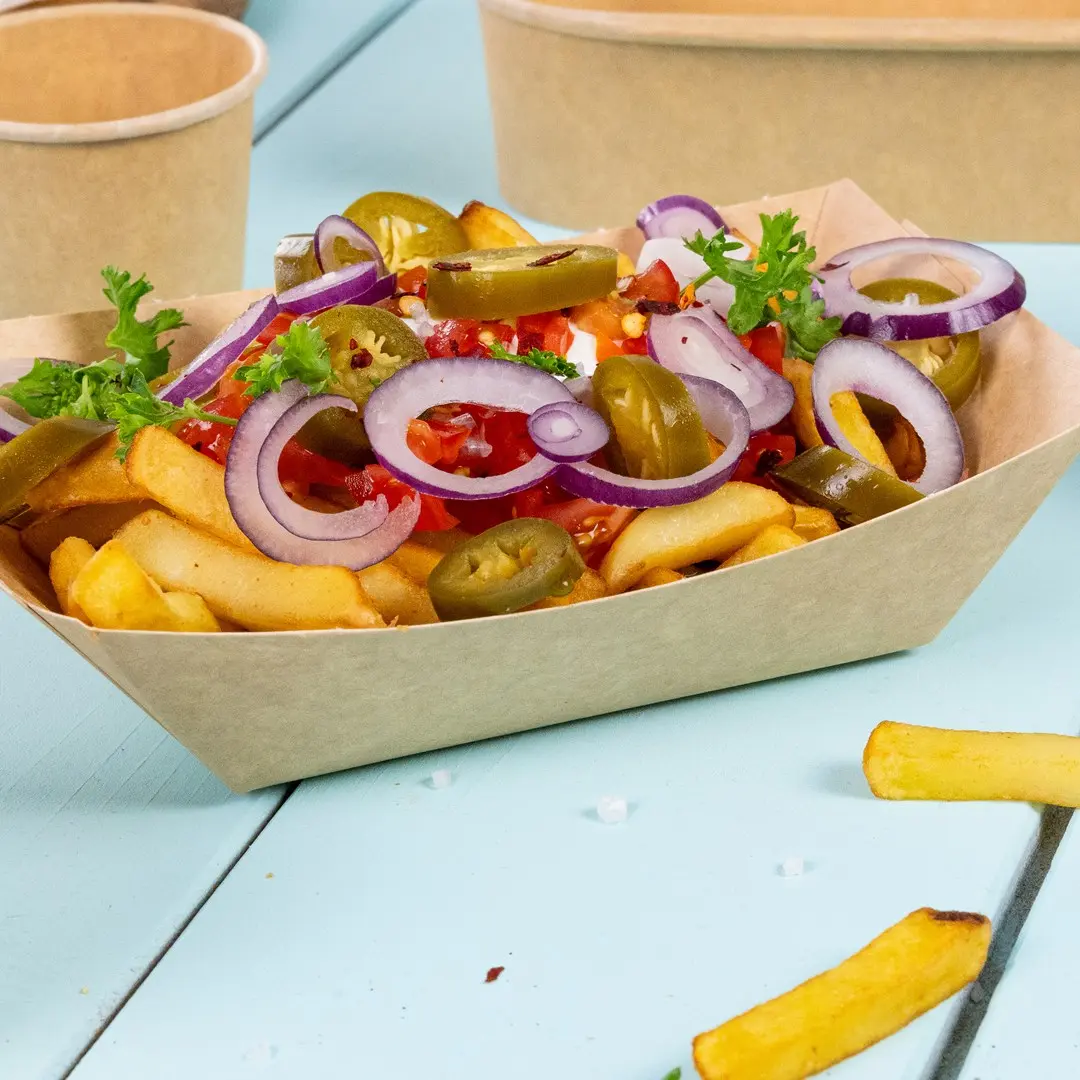 Bol de frites surmonté d'oignons tranchés, de jalapeños, de tomates en dés et de persil sur une surface bleue.