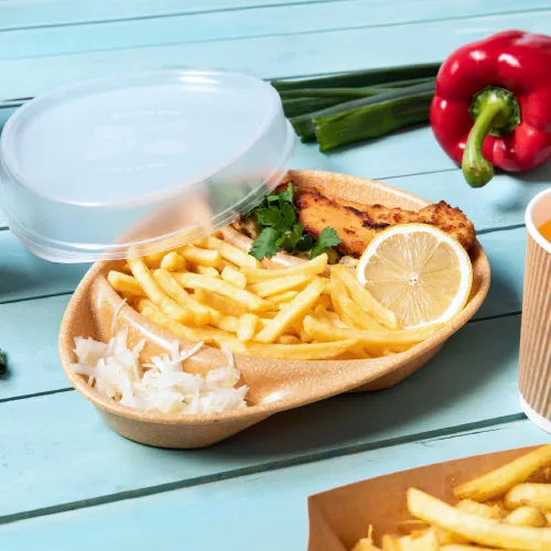 Conteneur alimentaire avec du poisson frit, citron, frites et salade, accompagné d'oignons verts et d'un poivron rouge.