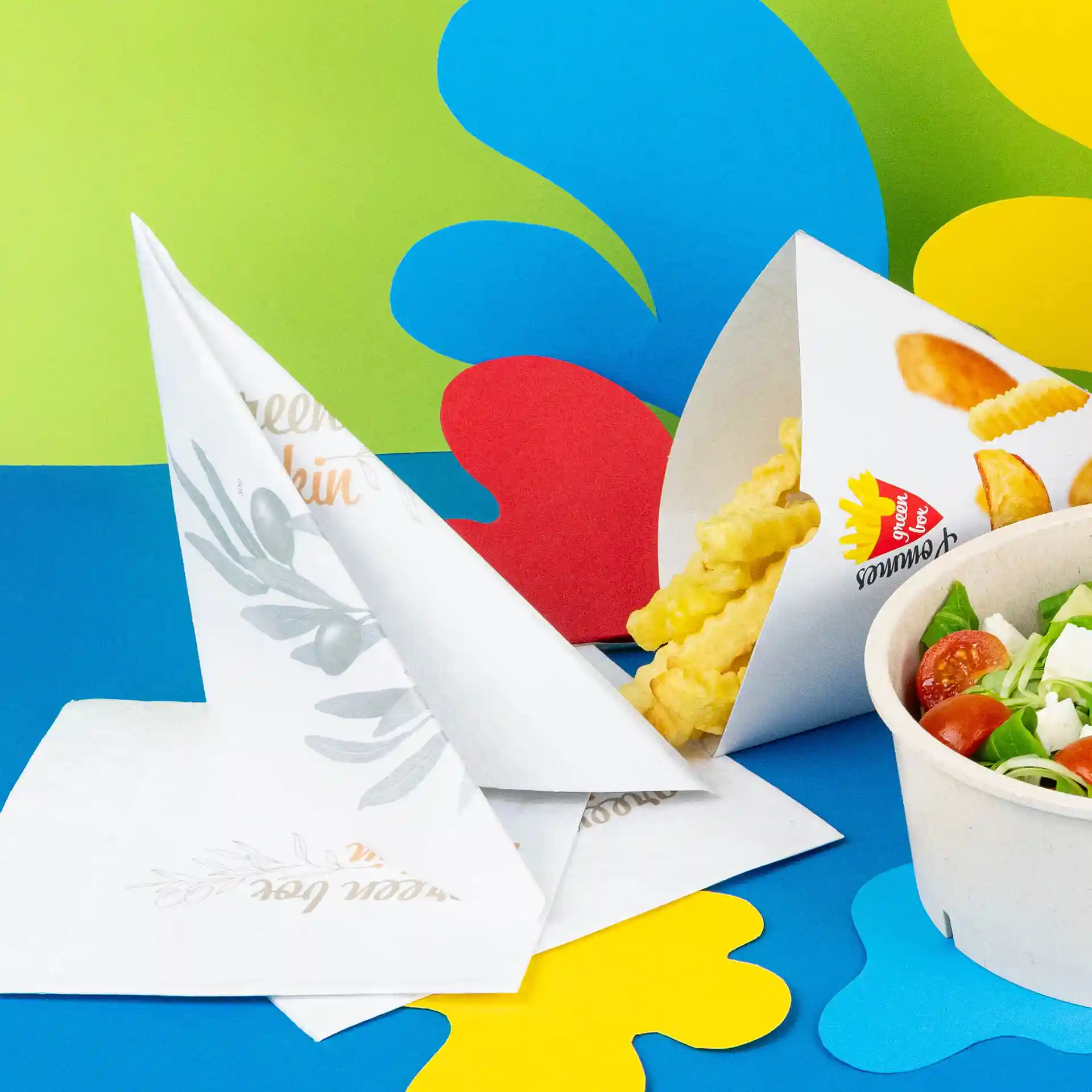 Image de serviettes imprimées en quart de pli, avec des frites ondulées et un bol de salade sur un fond coloré.