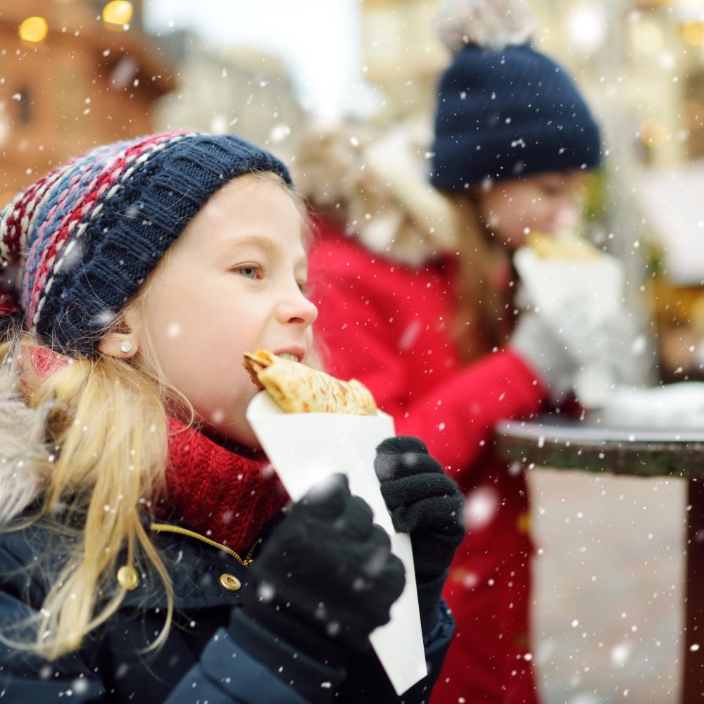 Mdchen isst Crepe auif dem Weihnachtsmarkt