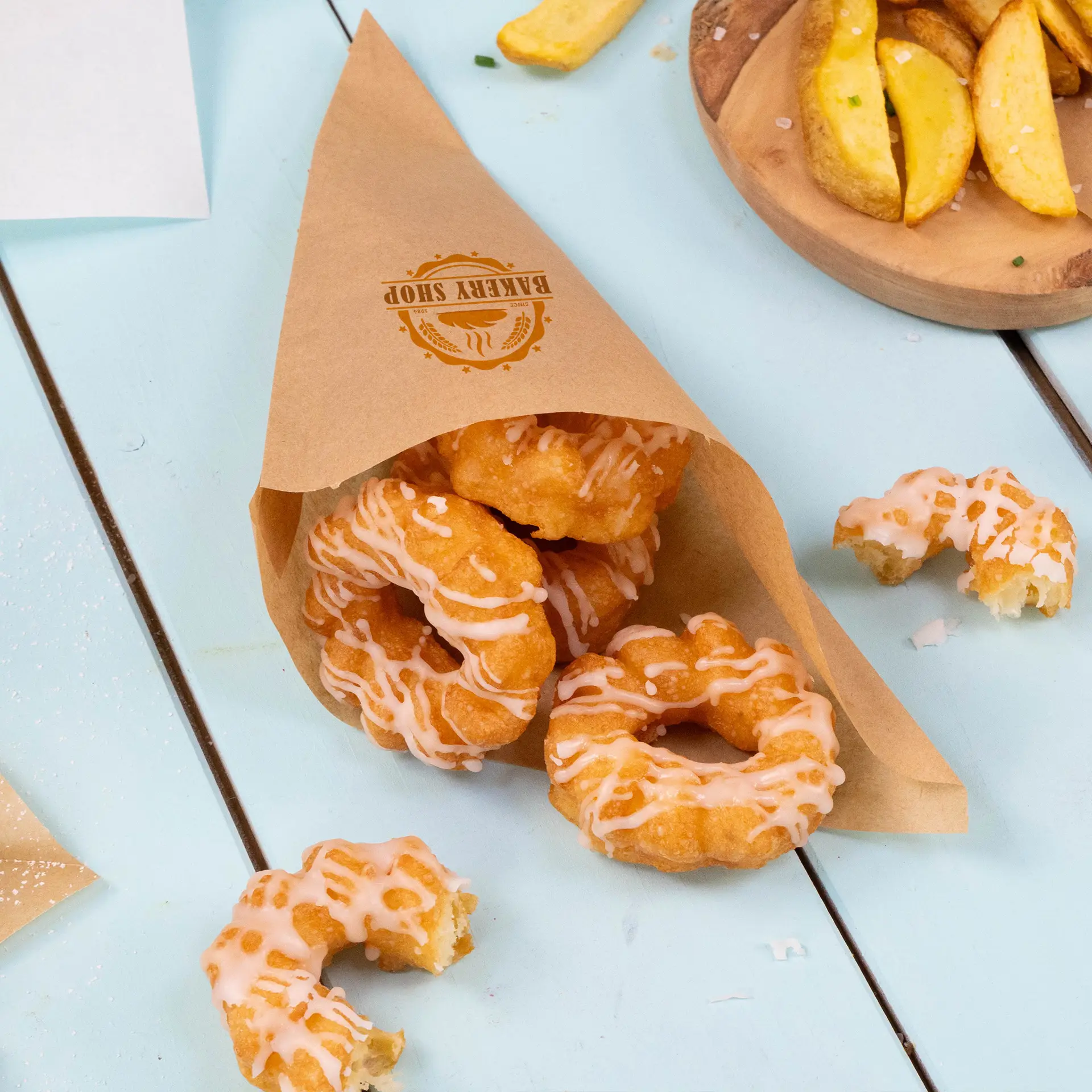 Sac conique en papier brun contenant des donuts glacés, avec un logo visible sur le côté, placé sur une surface bleue.