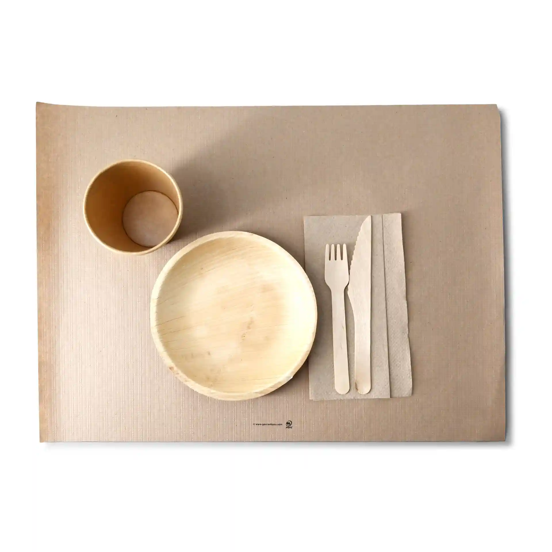 Image d'un set de table en papier avec un bol, une tasse, une fourchette en bois, un couteau et une serviette disposés dessus.