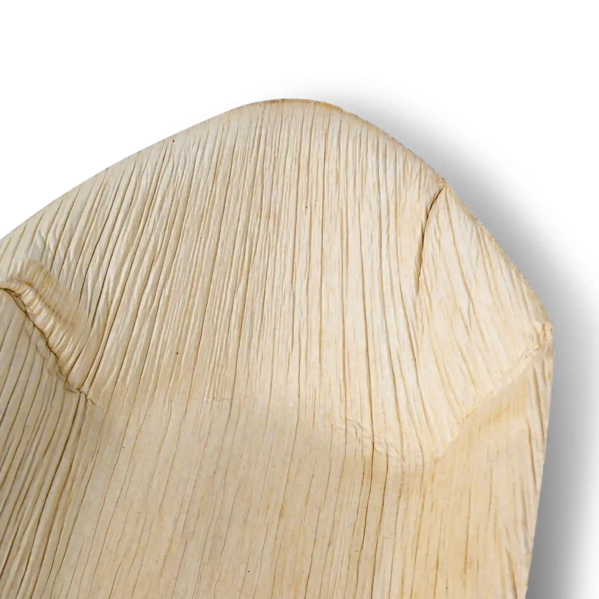 Gros plan d'un plat en forme de bateau en feuille de palmier avec une surface texturée, montrant le grain et les bords naturels.