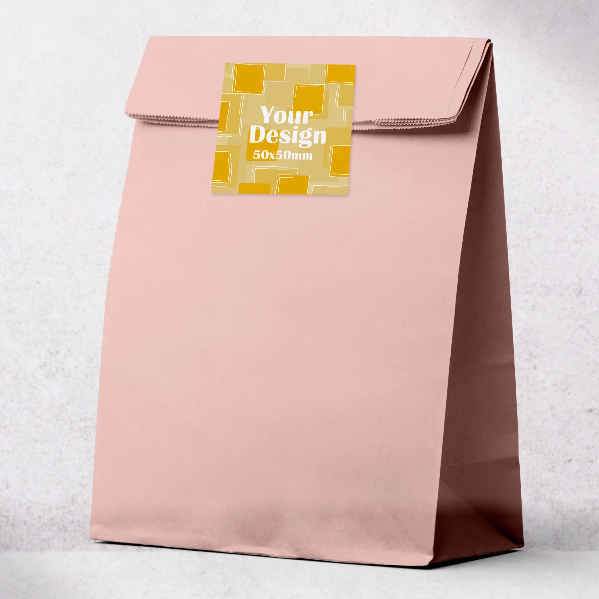 Sac en papier rose personnalisable avec une zone d'étiquette carrée, conçu pour l'impression personnalisée, sur un fond clair.