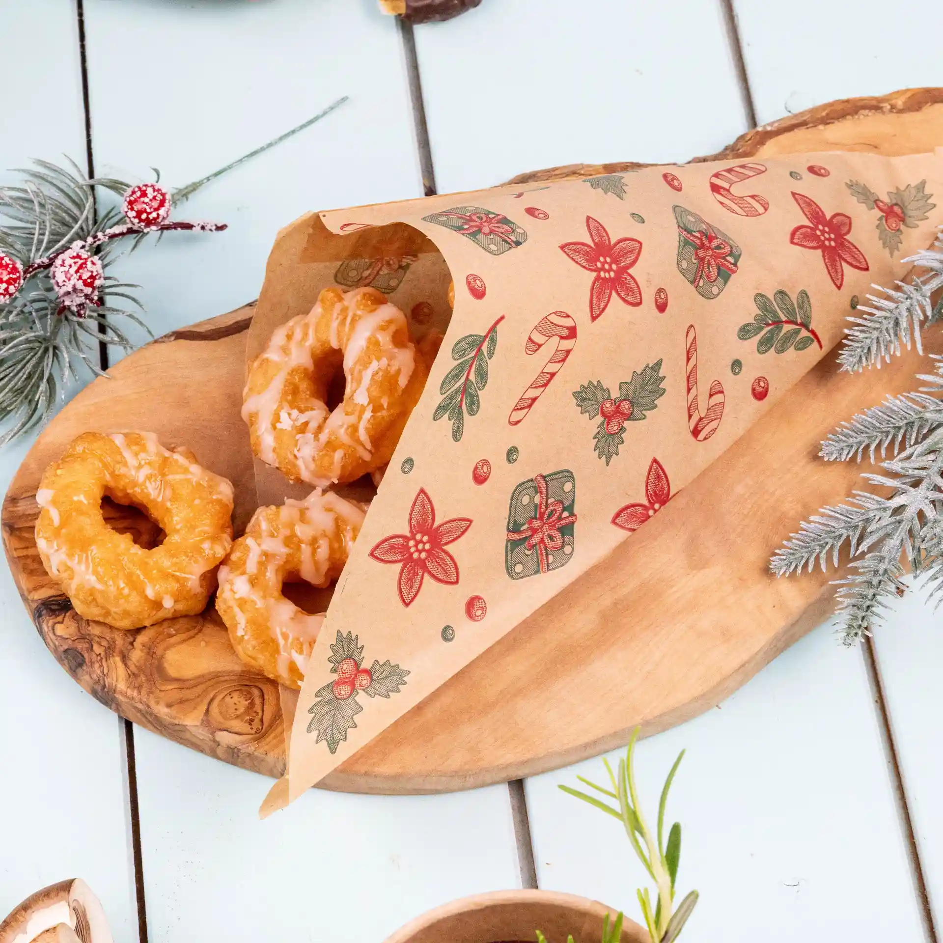 Sac brun résistant à la graisse avec un design d'hiver, contenant trois beignets glacés sur un plateau en bois.