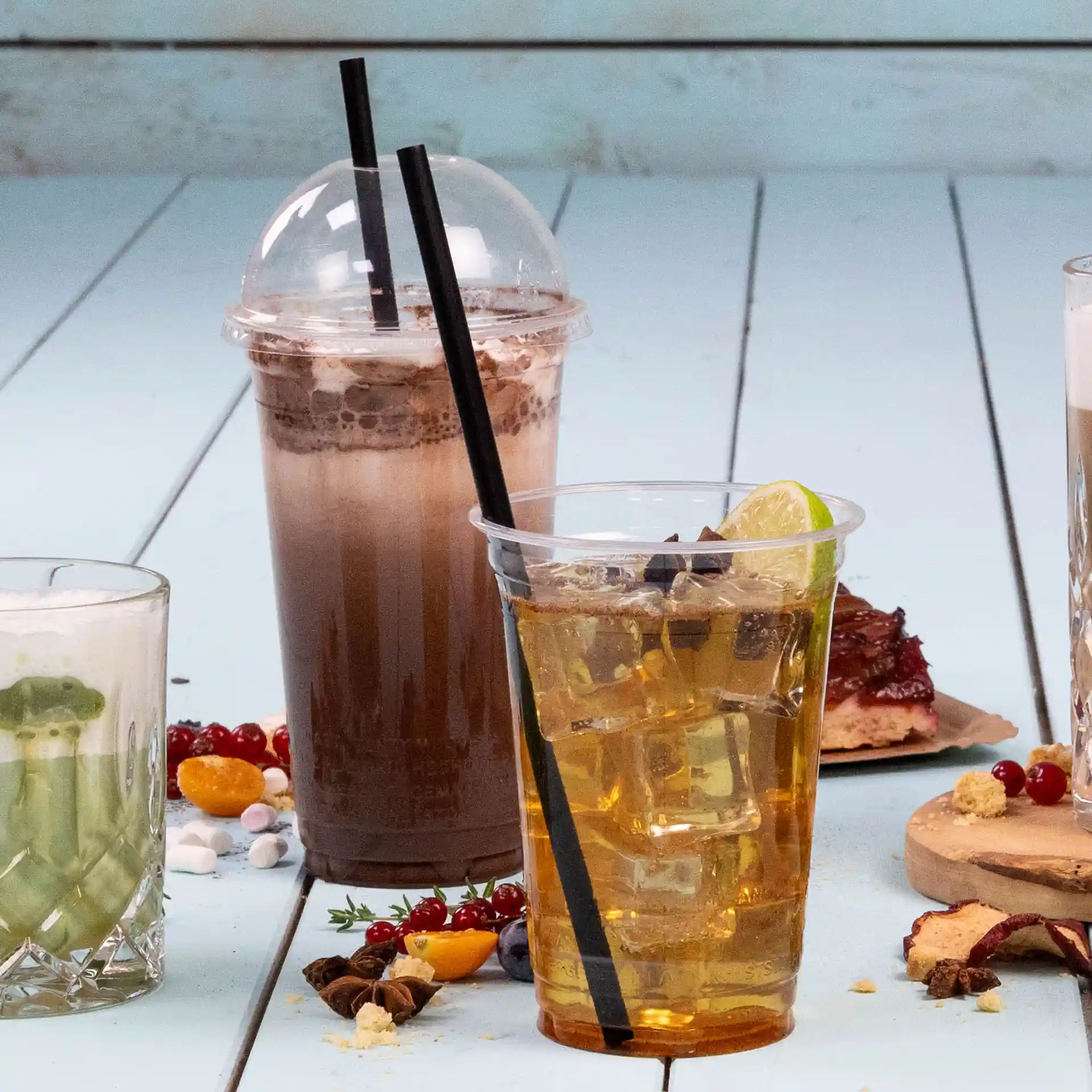 Image de trois boissons : une boisson au chocolat dans un verre transparent, une boisson glacée avec une tranche de citron et une boisson verte dans un verre.