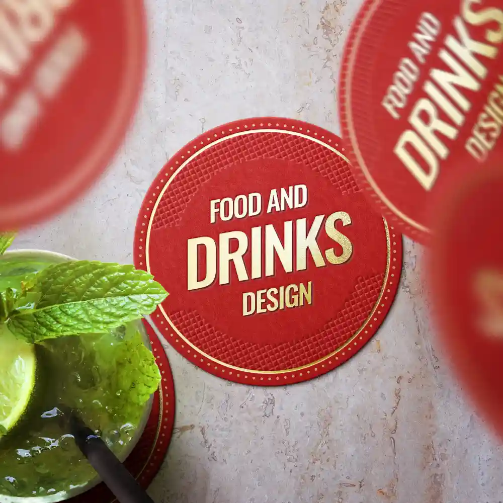 Sous-verre rouge avec le texte « Food and Drinks Design », placé près d'une boisson avec de la menthe et du citron vert.