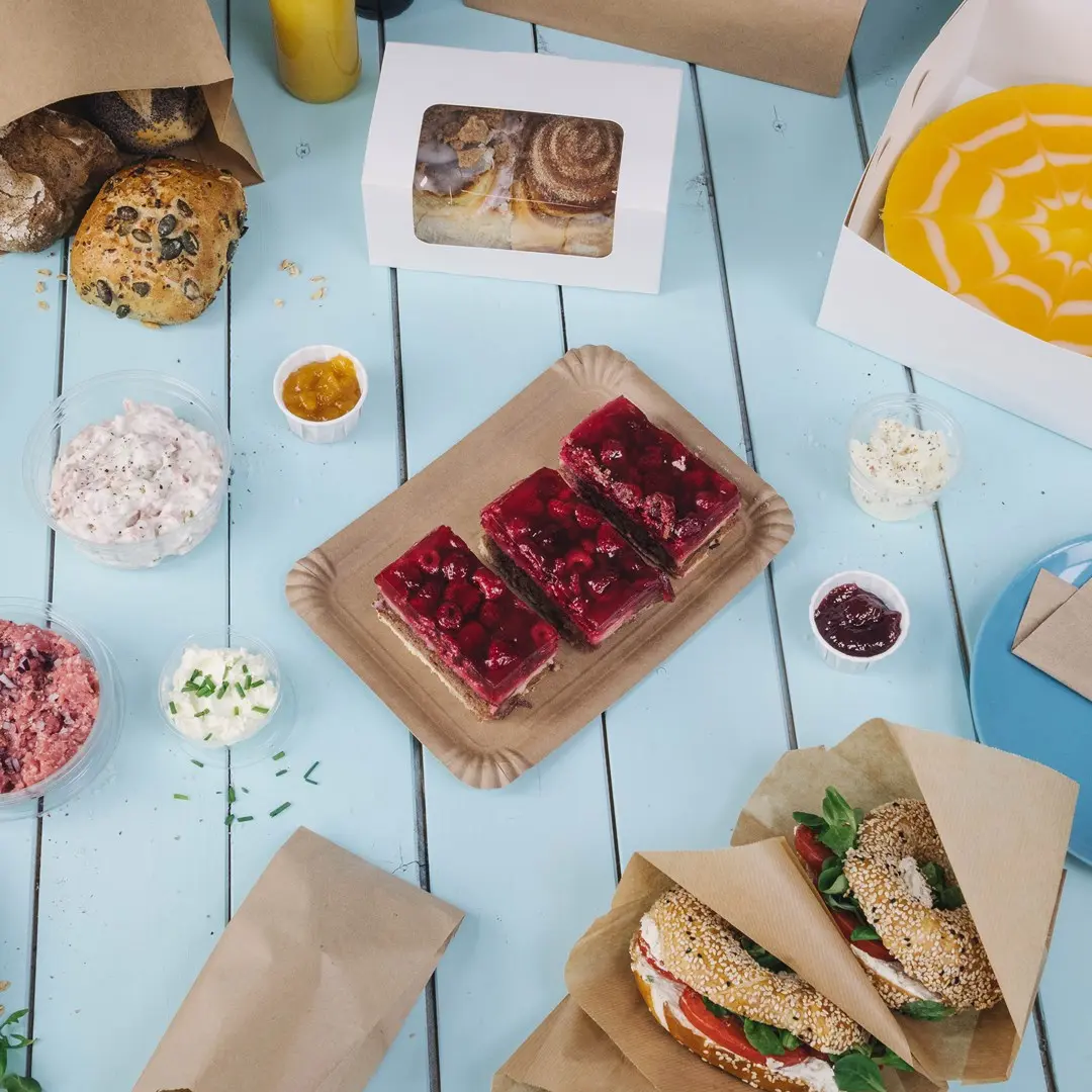 Pâtisseries et desserts variés sur une table bleue, y compris des gâteaux en gelée, des sandwiches et des dips dans des contenants.