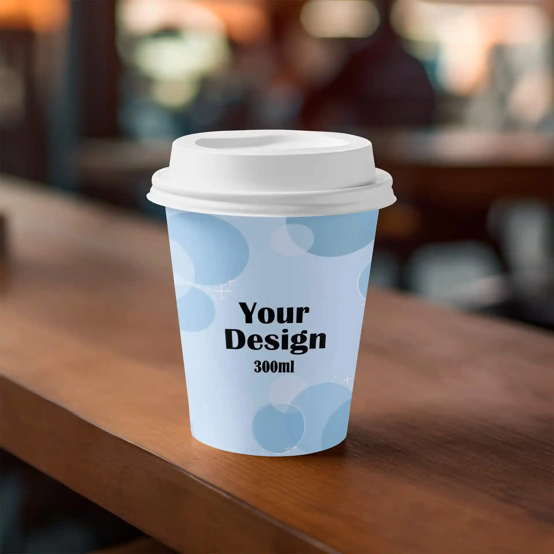 Gobelet en papier avec un couvercle blanc, présentant un design bleu clair et un texte noir, posé sur une surface en bois.