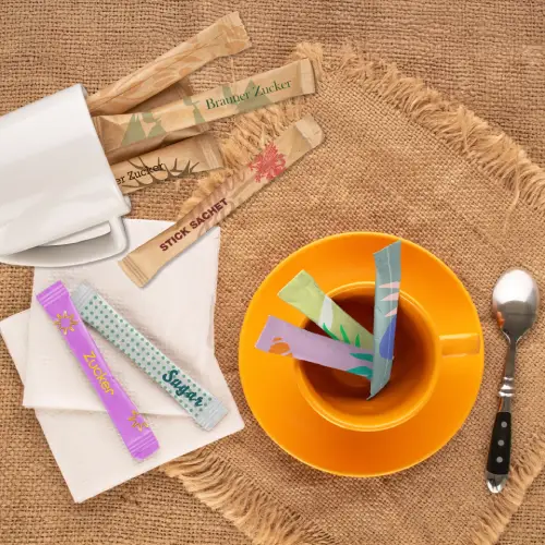 Sachets de sucre colorés dans une tasse de thé sur une table rustique avec une cuillère et des tasses vides.
