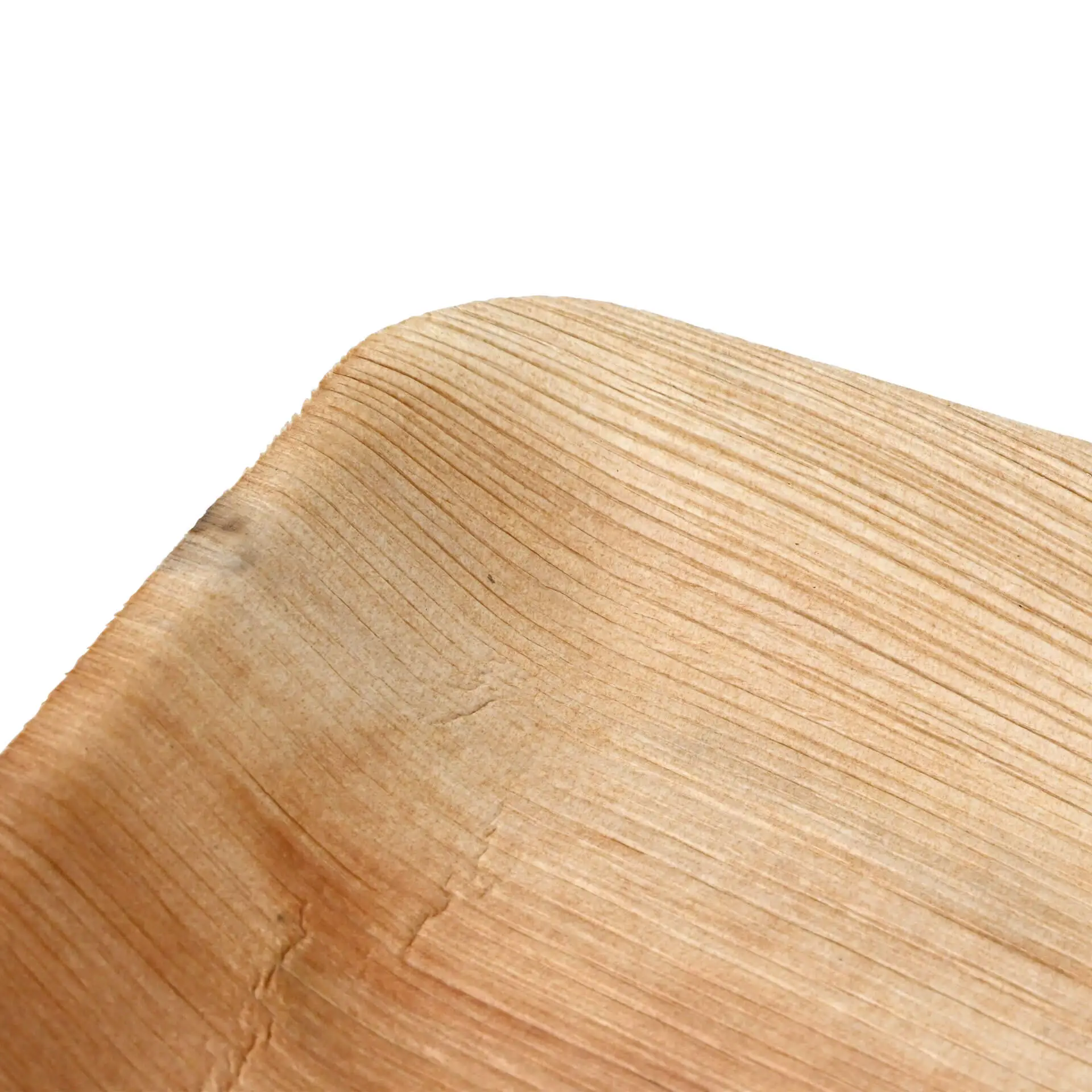 Gros plan d'une assiette plate en feuille de palmier avec une texture de grain de bois naturel, montrant le bord courbé et la surface lisse.