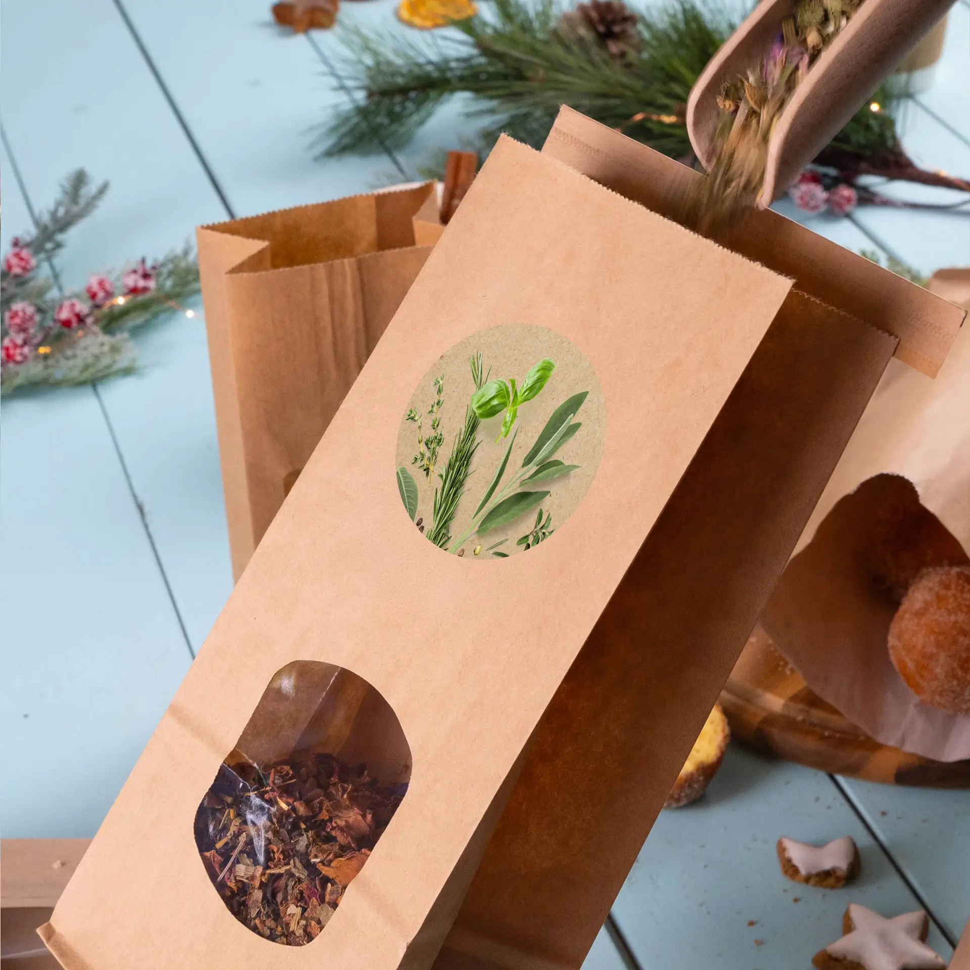 Sac en papier kraft marron avec une fenêtre ronde montrant des herbes séchées, étiqueté avec une illustration botanique en haut.