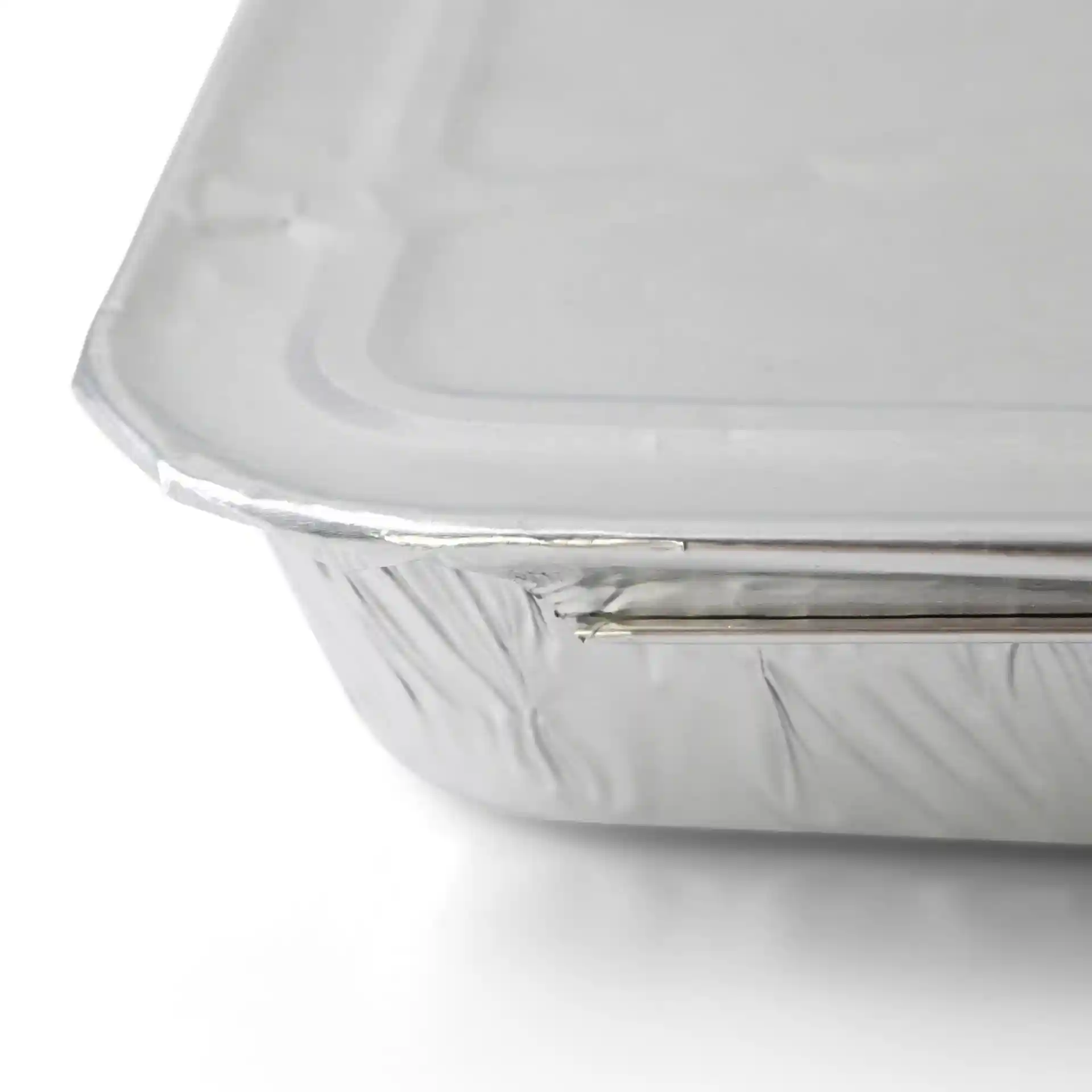 Couvercle en aluminium pour un plateau repas rectangulaire à deux compartiments, montrant les détails des bords et de la surface.