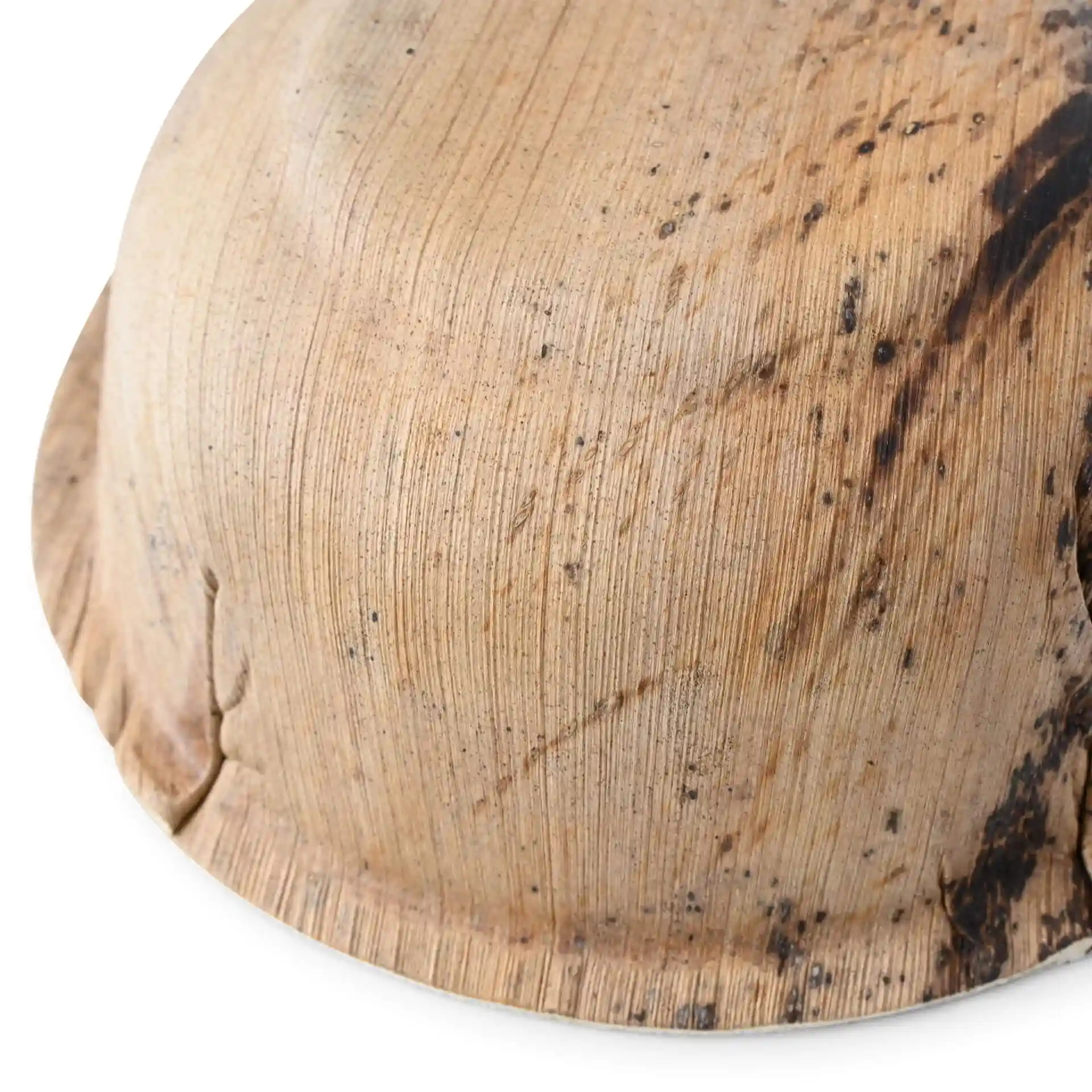 Gros plan d'un bol rond en feuille de palmier avec une surface texturée et une légère marque sombre.