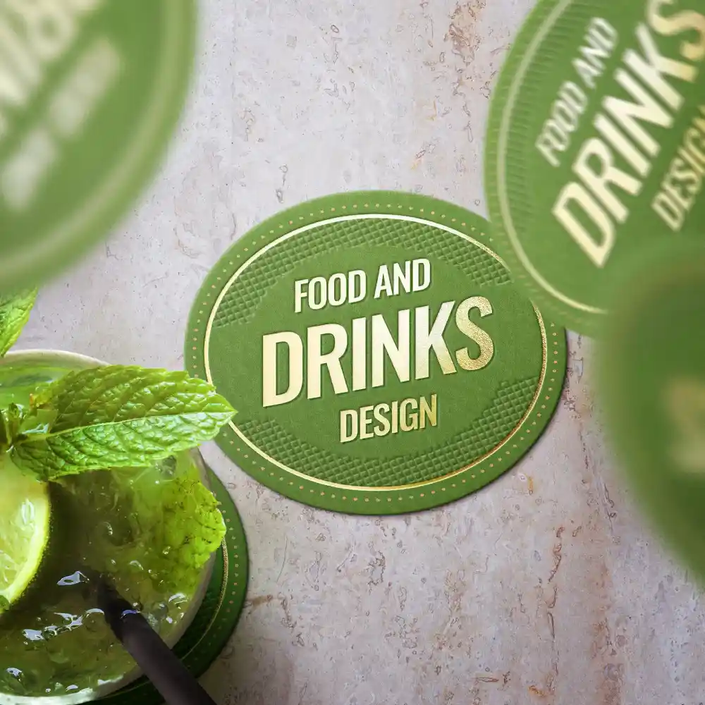 Sous-verre circulaire vert avec le texte "Design Alimentaire et Boissons" et une boisson contenant de la menthe et du citron vert au premier plan.