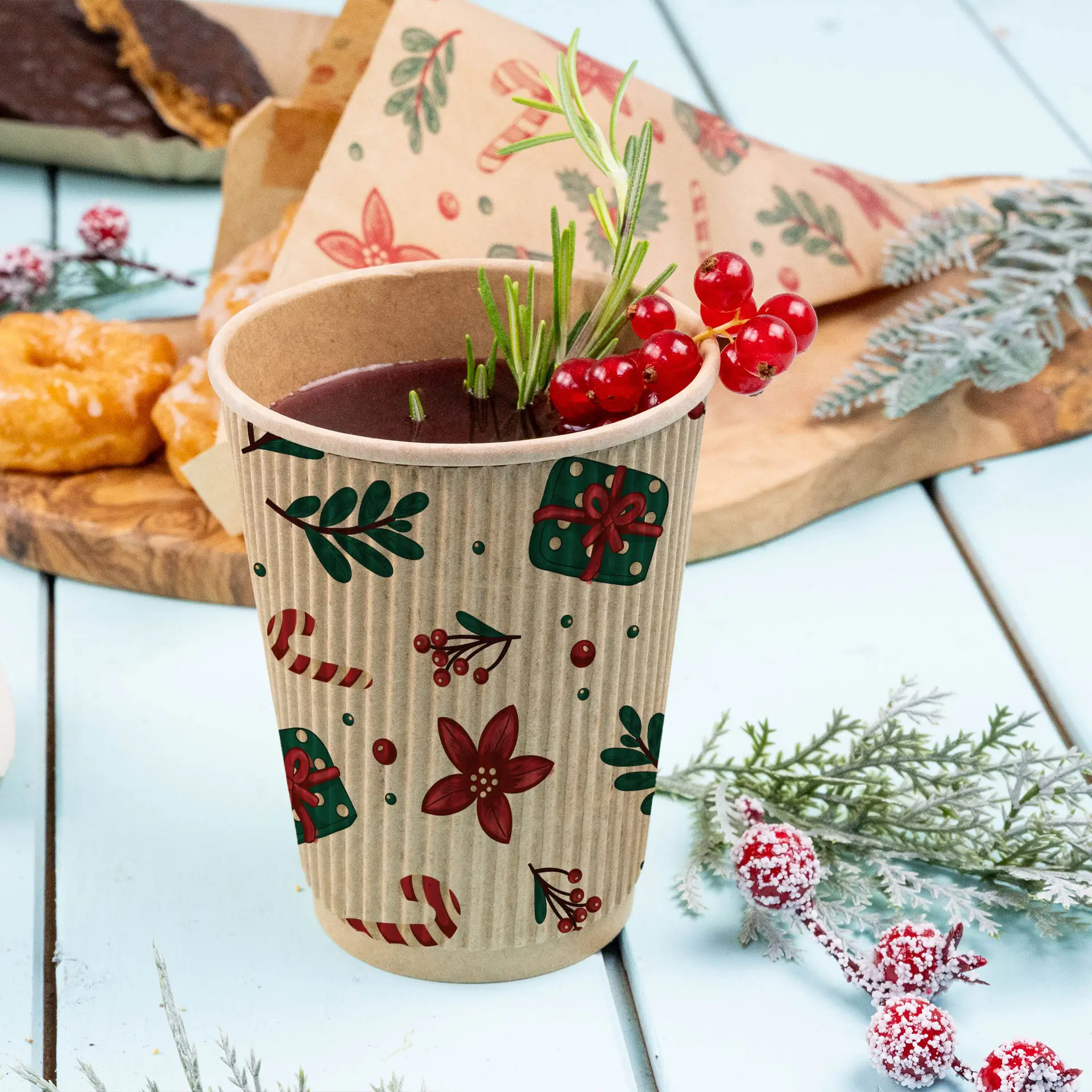 Tasse brune à motifs d'hiver, remplie d'une boisson et garnie de baies rouges et de romarin, sur une surface bleu clair.