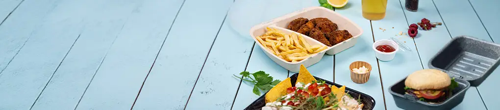Personnage de chef avec une tête verte et un chapeau blanc, tenant une cuillère ; deux contenants alimentaires avec un hamburger et un repas avec des frites et du poulet sur un fond en bois bleu.