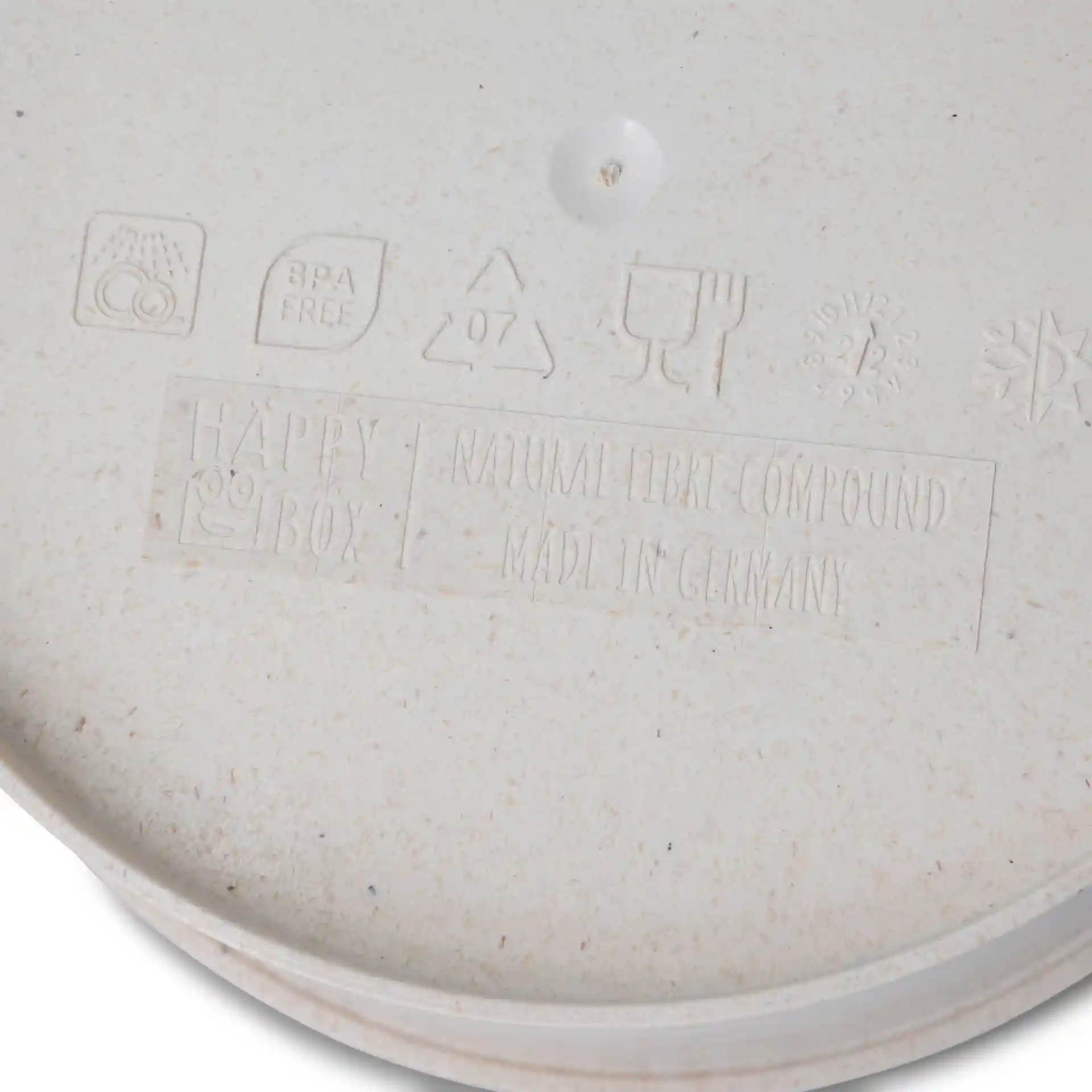 Bol rond crème réutilisable en composé bio, montrant des marques et symboles en relief au fond.