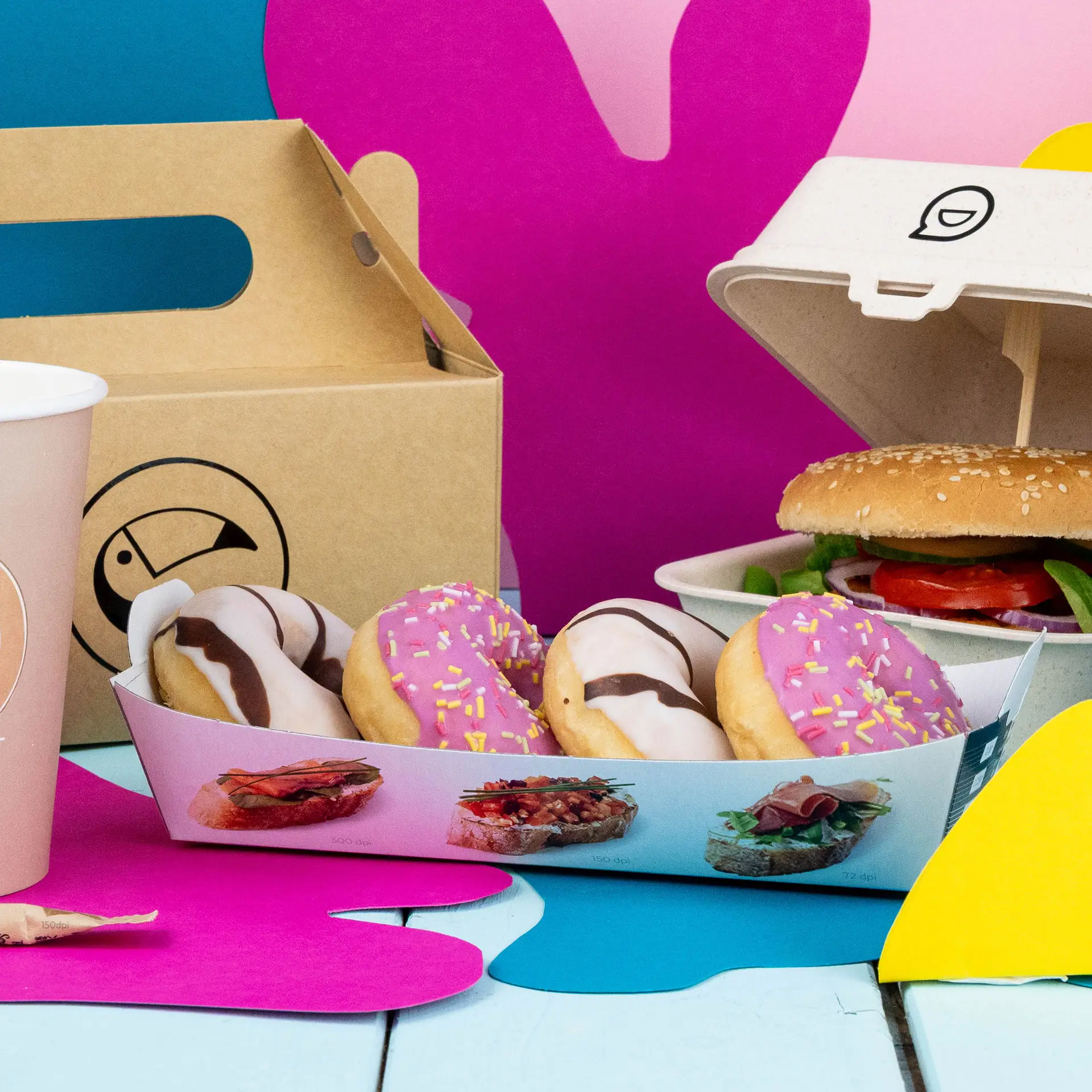 Plateau à snacks en carton rectangulaire imprimé avec quatre donuts, un burger et une tasse de café sur un fond coloré.