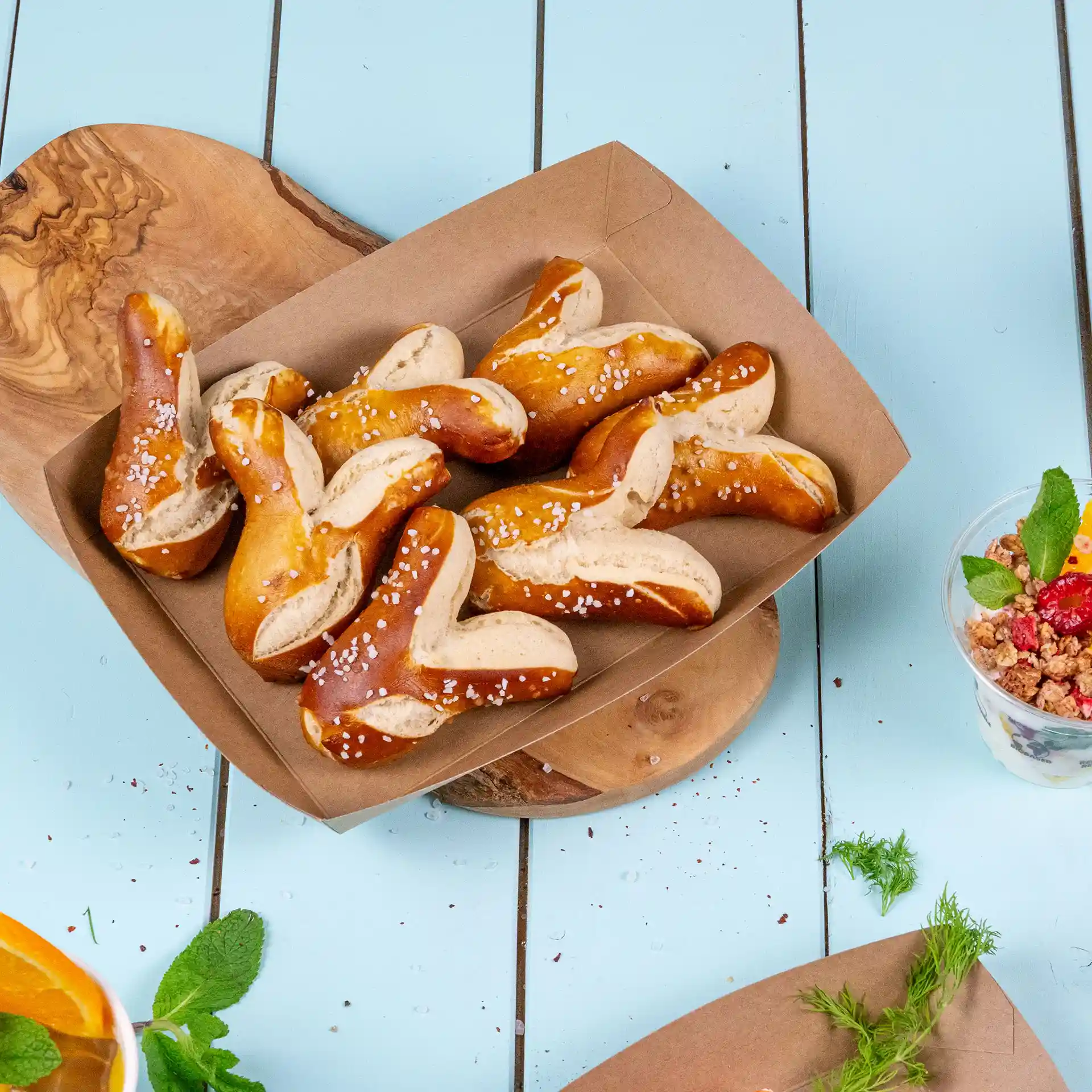 Un plateau en carton brun rempli de plusieurs morceaux de bretzel garnis de gros sel.