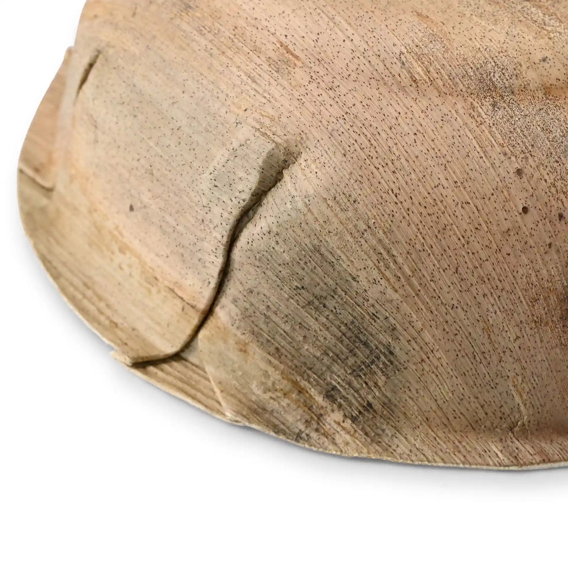 Gros plan d'un bol rond en feuille de palmier avec une texture granuleuse et des coutures visibles à la surface.
